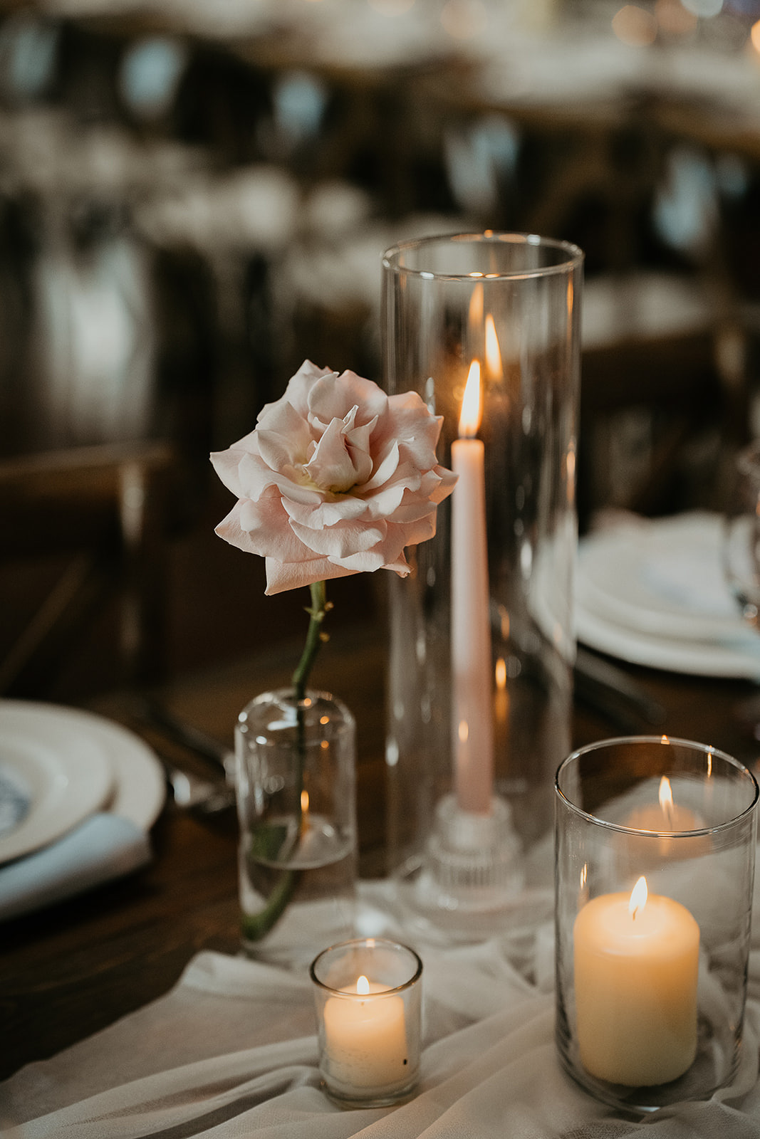 A rose, candles, and runner artfully placed on a long dining table.
