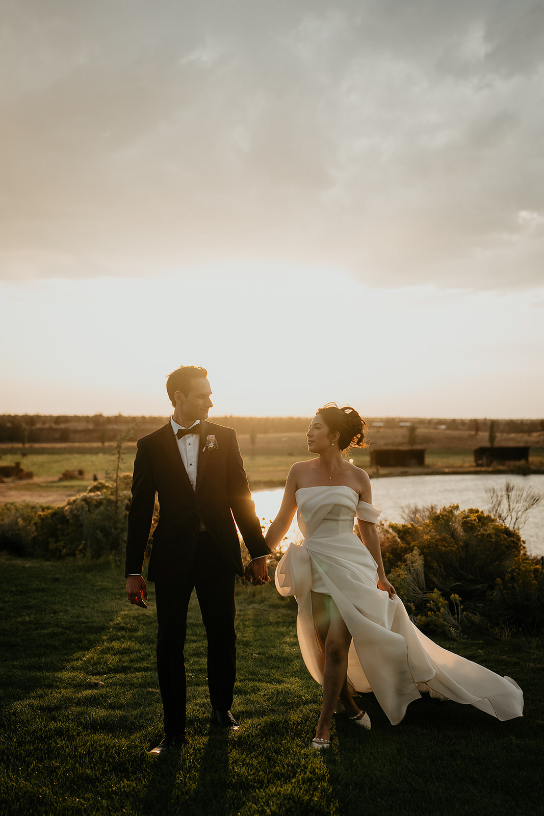 newlyweds holding hands at sunset with the Oregon desert in the background.