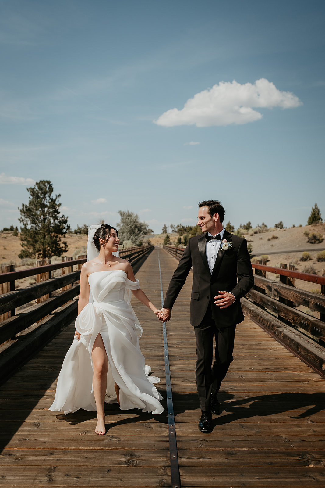 newlyweds walking across tressle bridge during their Brasada Ranch wedding.