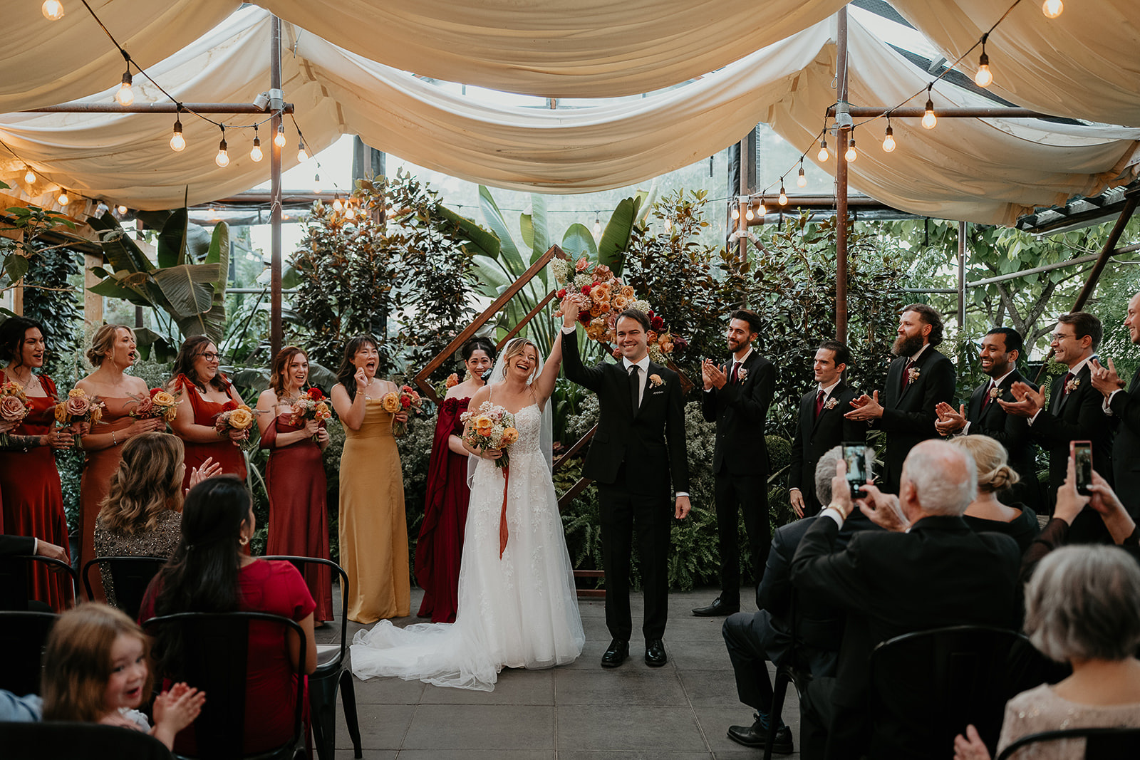 newlyweds raising their hands to the crowd after getting married at the Blockhouse wedding venue. 