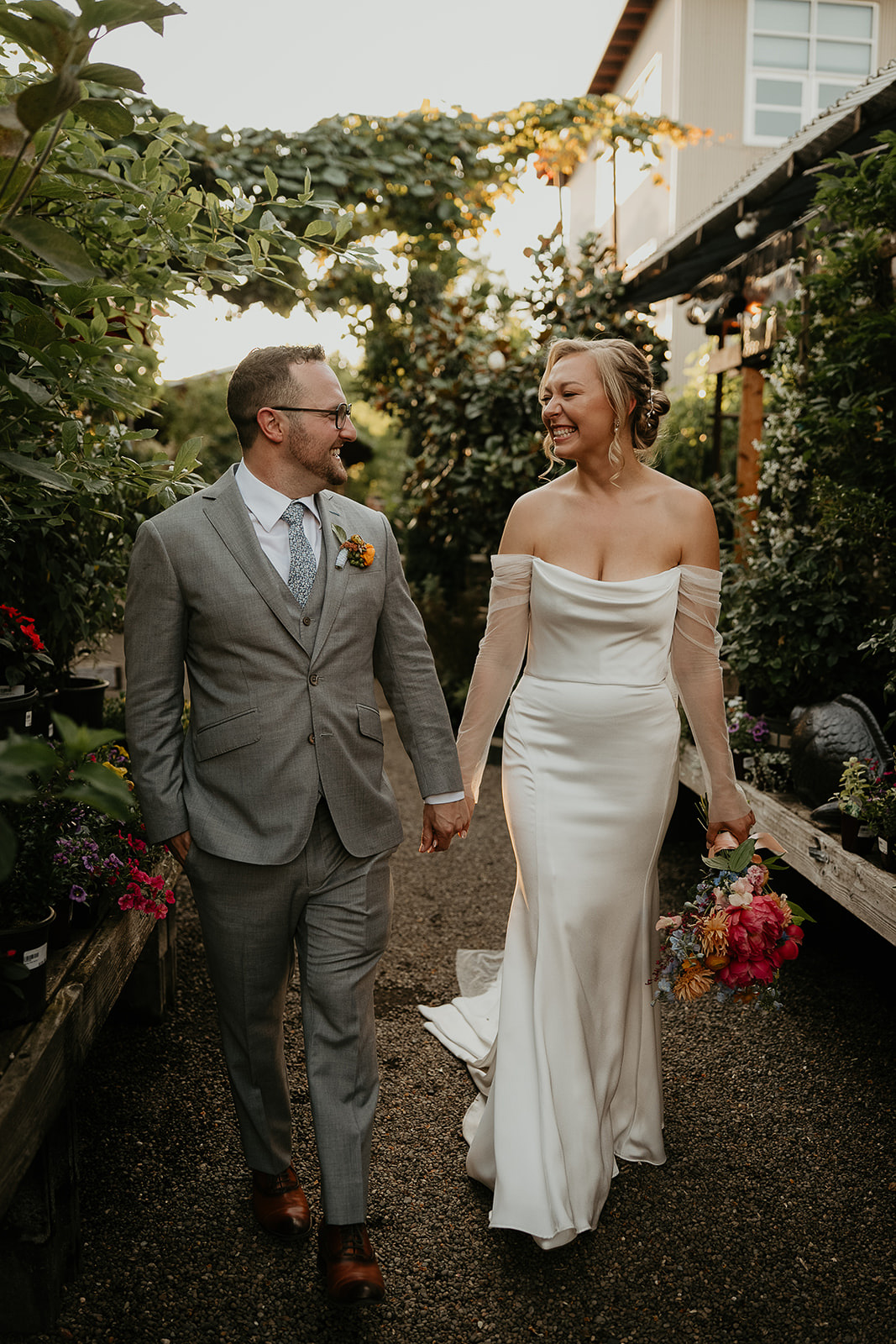 newlyweds walking on a dirt path inside a nursery by the Blockhouse wedding venue.