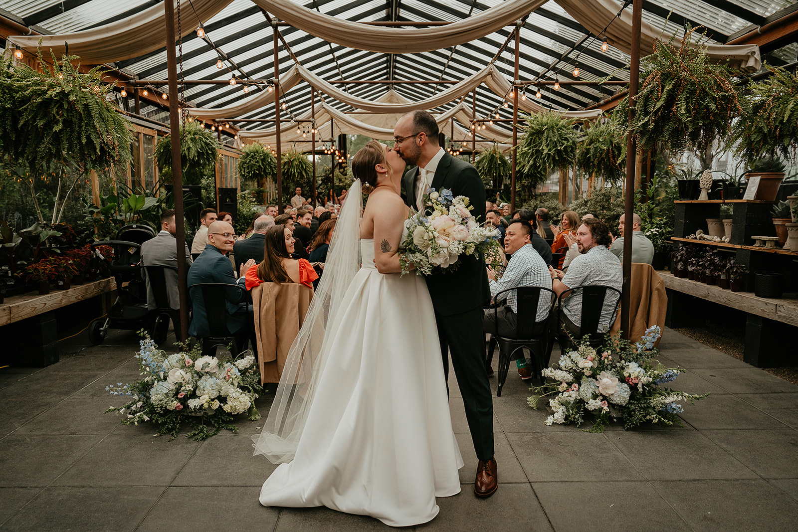 newlyweds kissing in a greenhouse by the Blockhouse wedding venue.