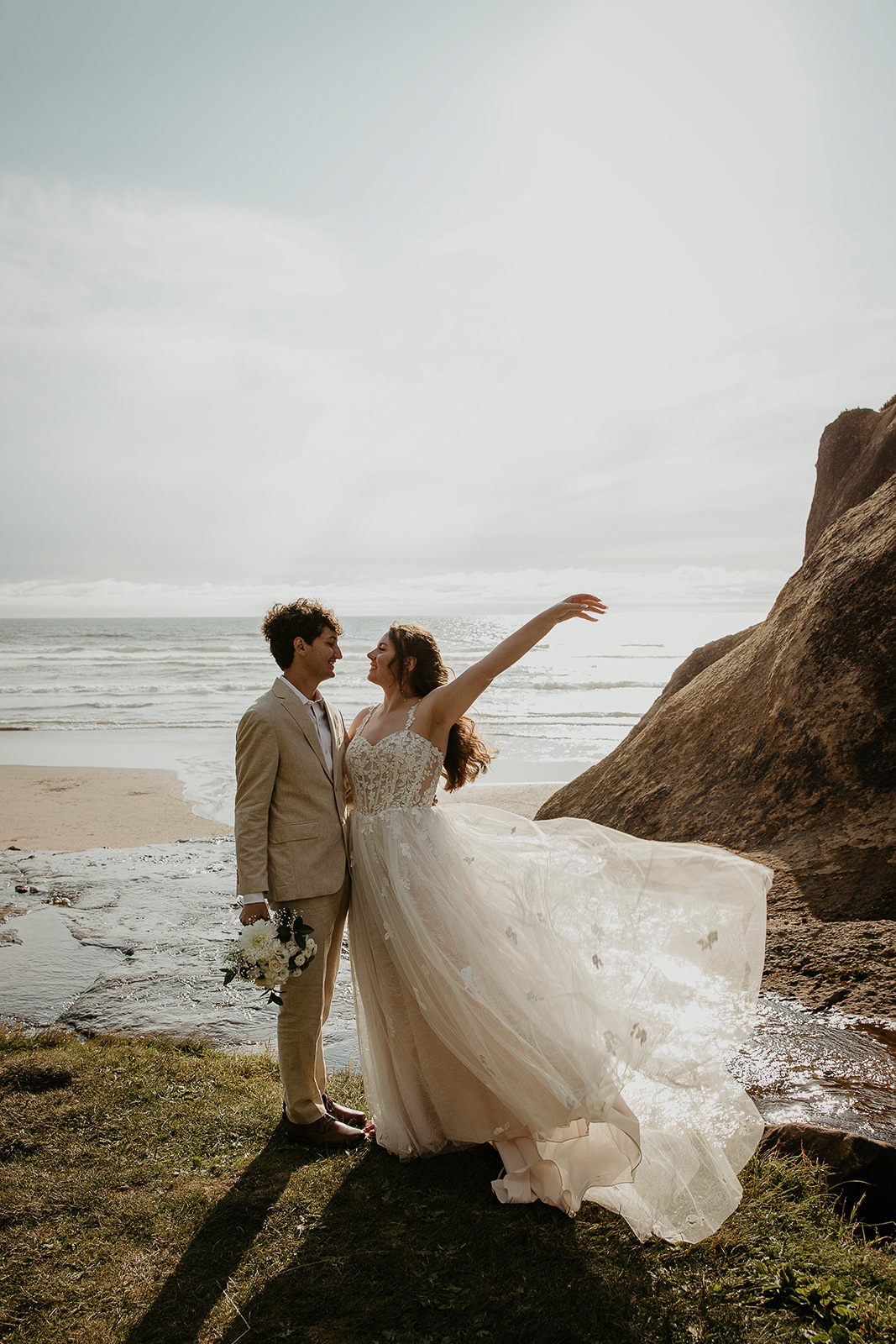 newlyweds standing on a cliffside above the Oregon coast.