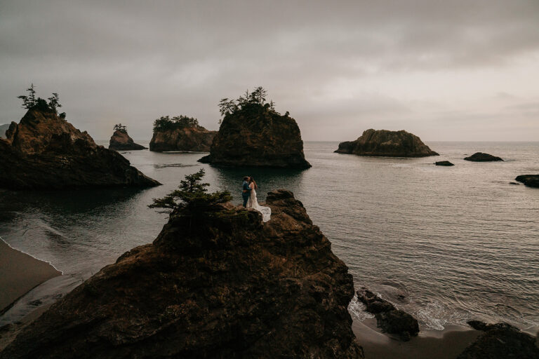 newlyweds standing on a cliffside along the southern Oregon coast, outside one of the area's gorgeous wedding venues.