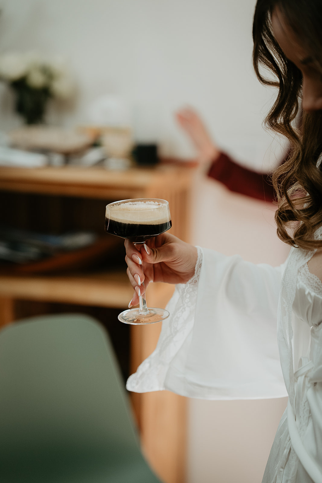 a bride holding an espresso martini as she gets ready