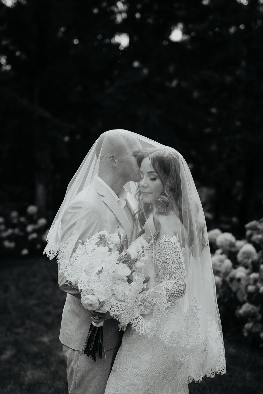the groom under the bride's veil kissing her forehead during their Rocky Hill Oregon wedding.
