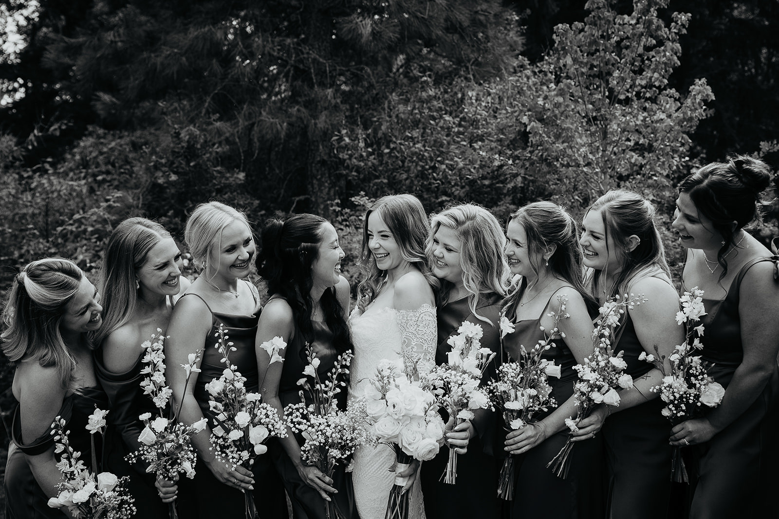 the bride and her bridesmaids smiling lined up next to each other.