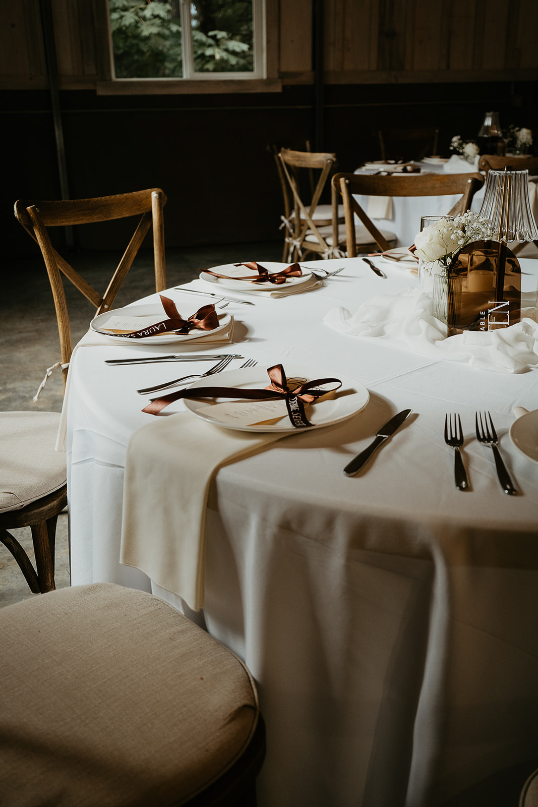 a dinner table with plates with ribbons, utensils, and napkins.