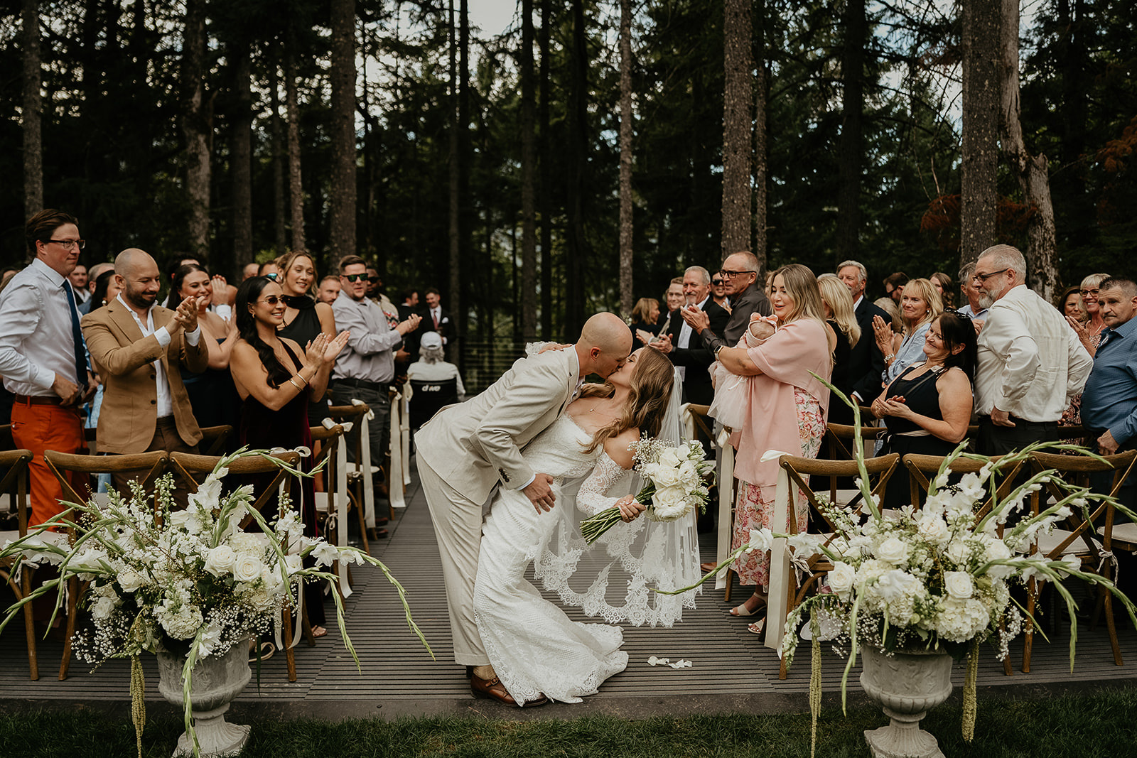 newlyweds kissing after their ceremony with their wedding guests clapping around them.