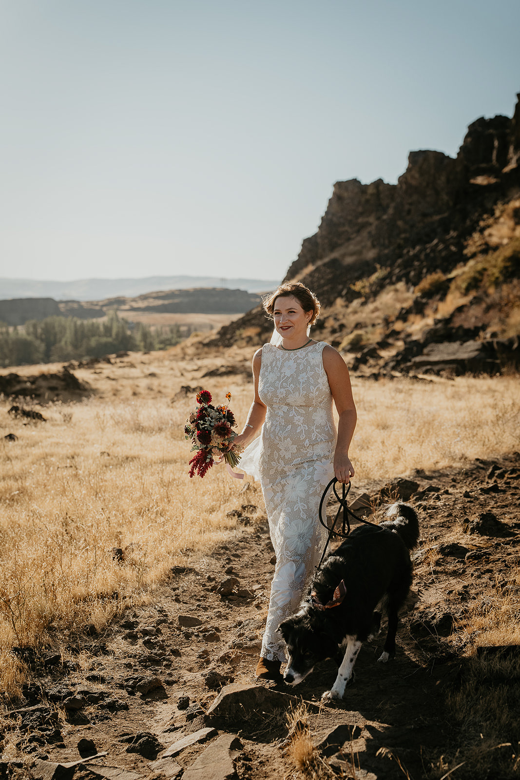 the bride walking along a dirt path with her dog.