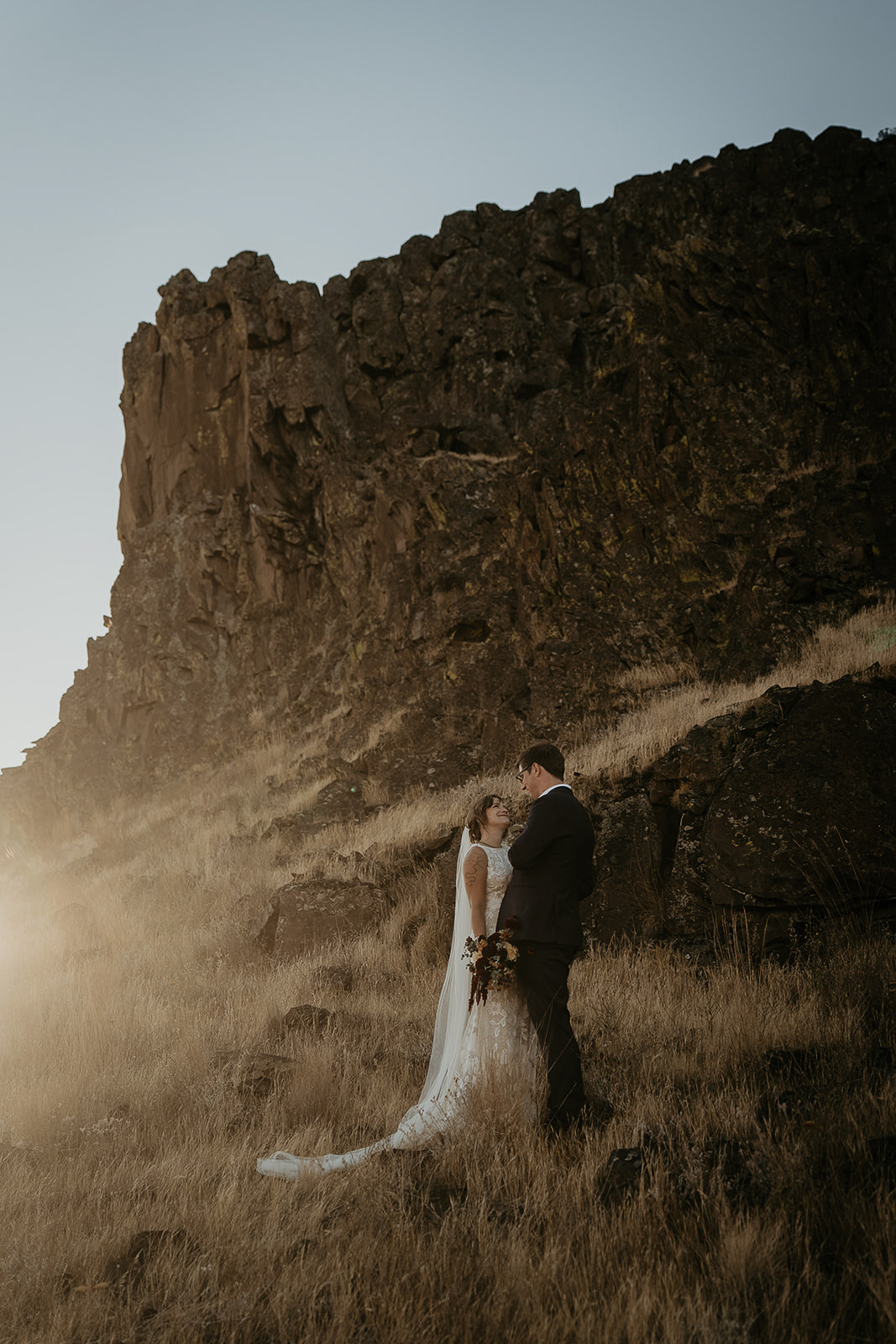 newlyweds holding each other next to a large butte.