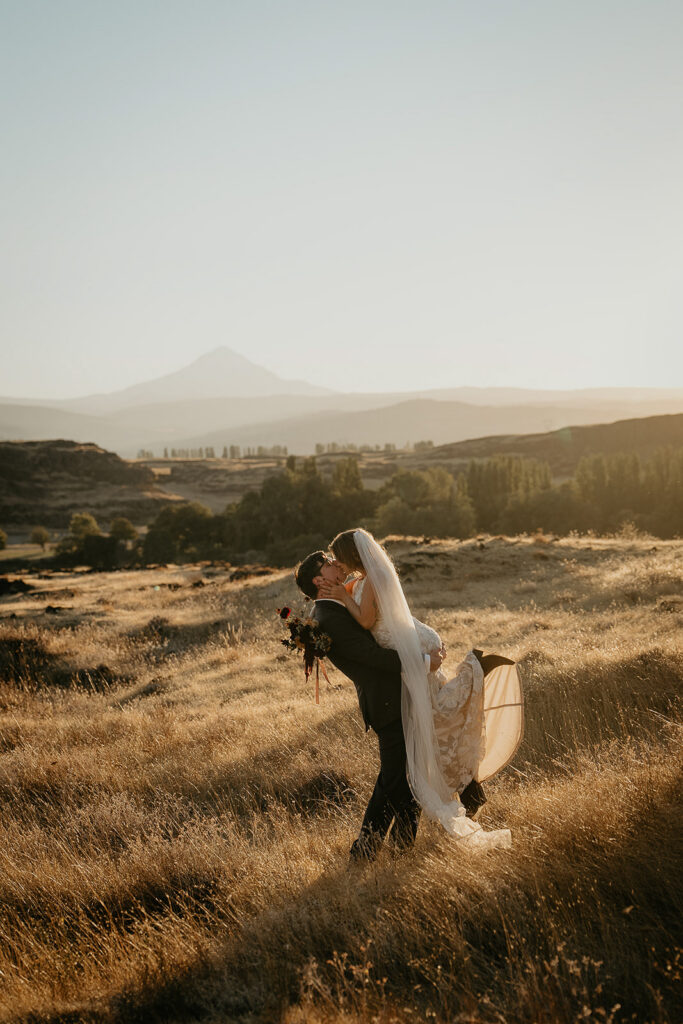 newlyweds kissing in a field of golden grass at sunset during their columbia river gorge elopement
