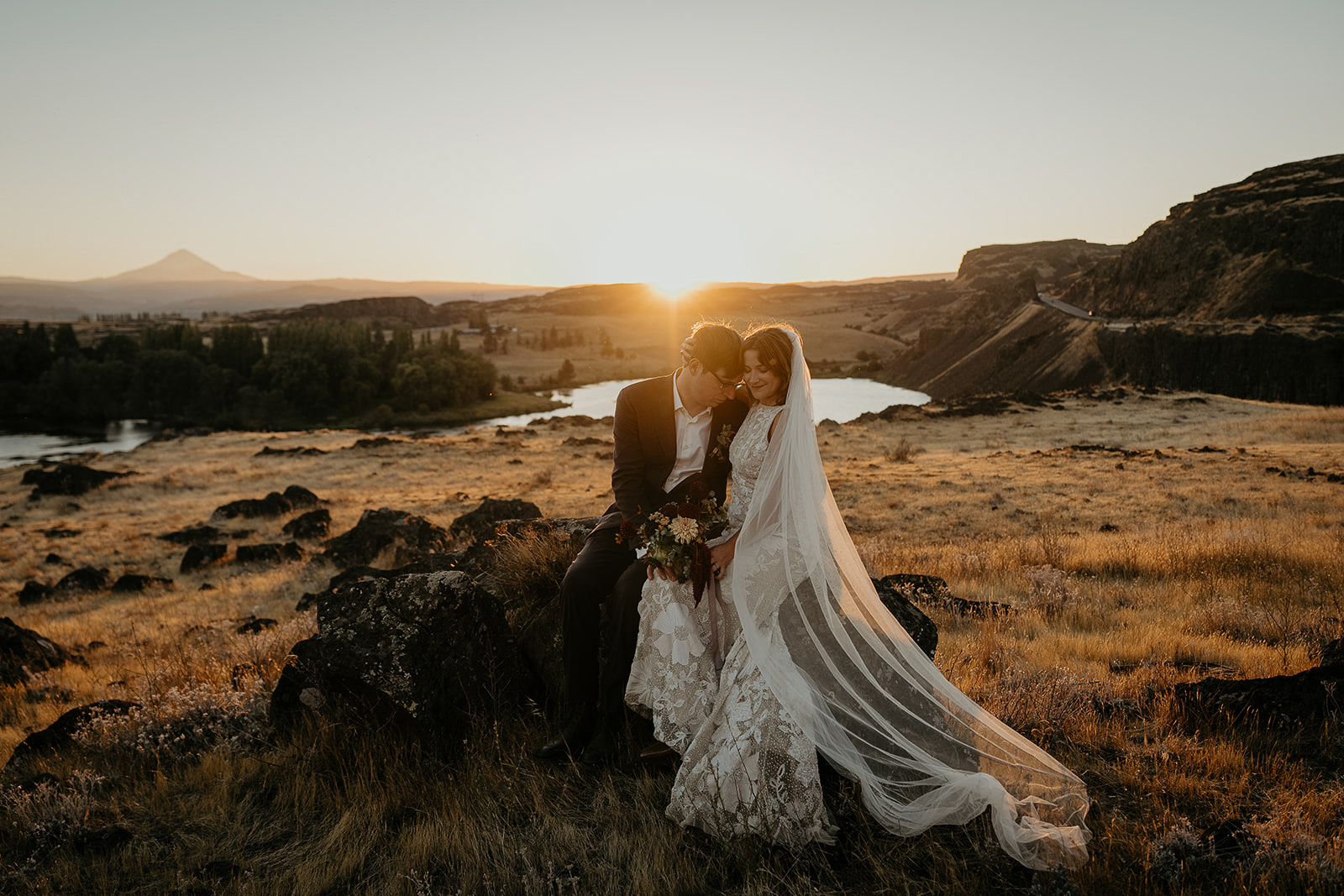 newlyweds hugging and sitting on a rock at sunset during their Columbia River Gorge elopement.