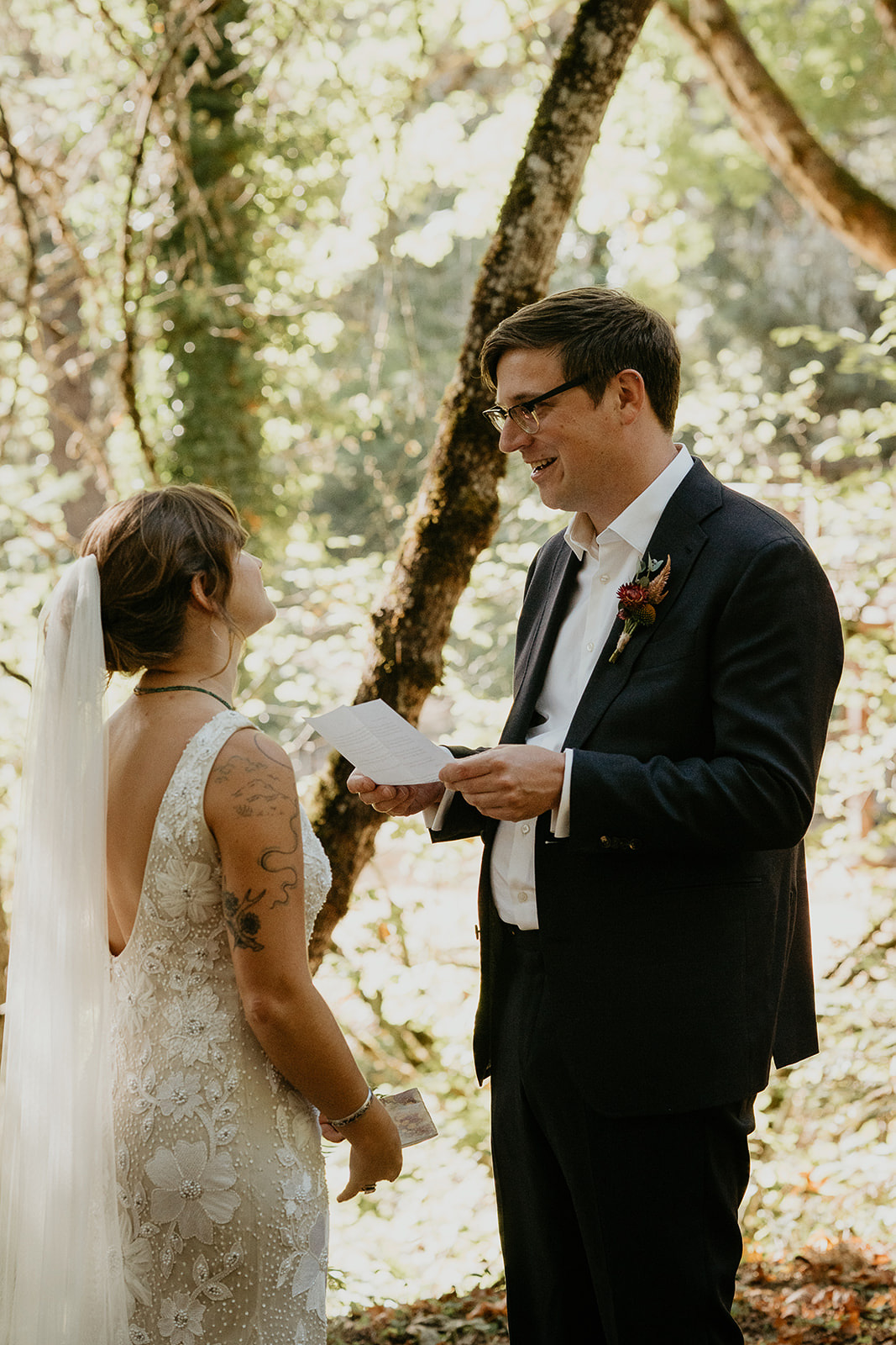 the groom reading from a letter while he has his first look in a forest.