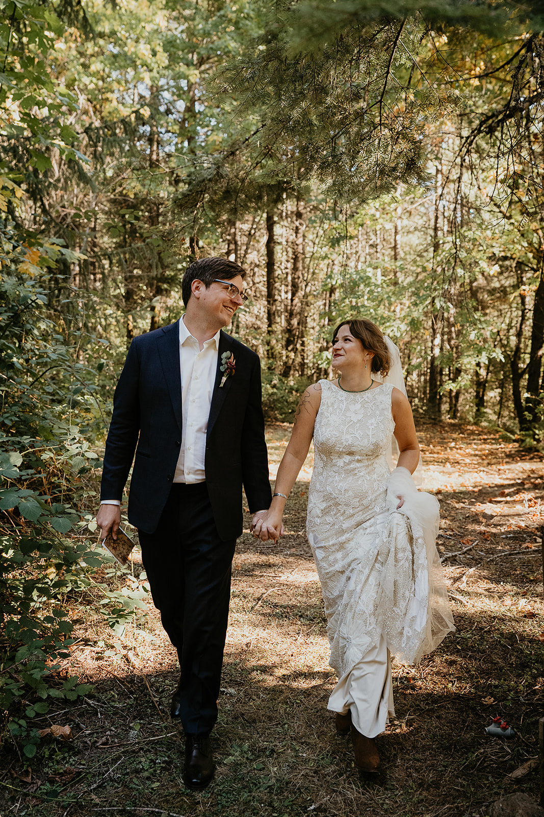 newlyweds holding hands walking along a forest path during their Columbia River Gorge elopement.