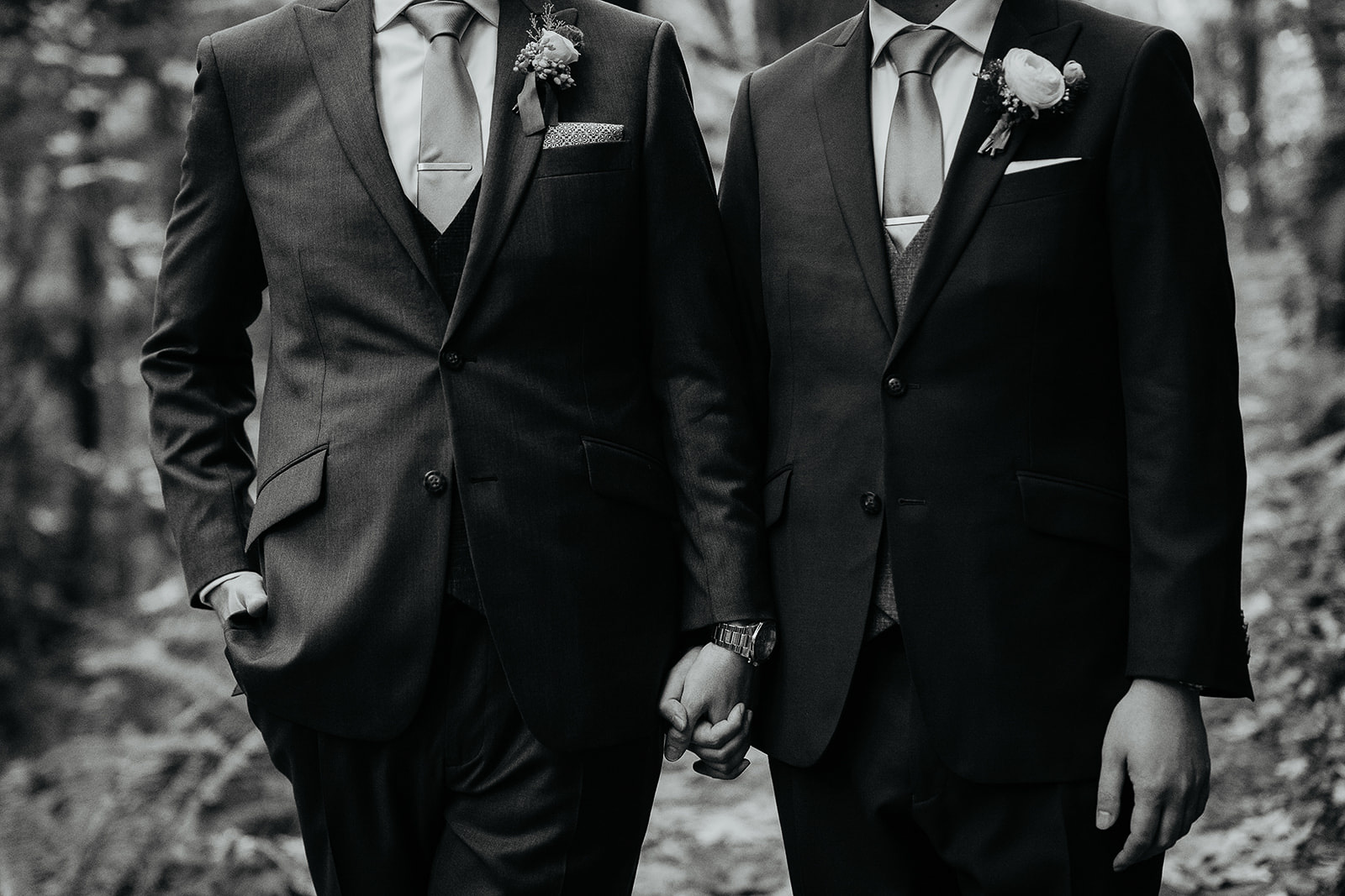 newlyweds holding hands on a forest trail.
