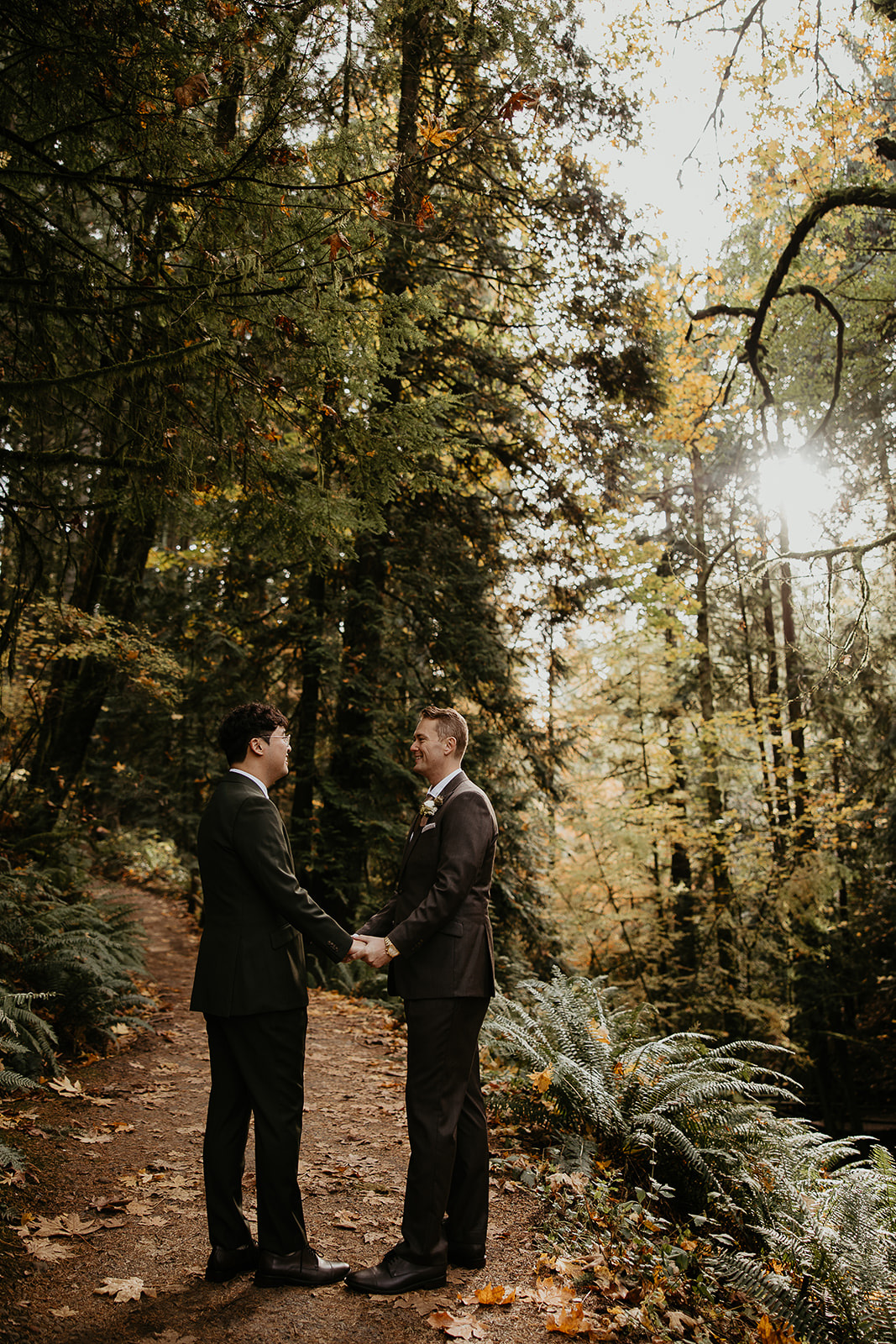 newlyweds holding hands on a forest trail.