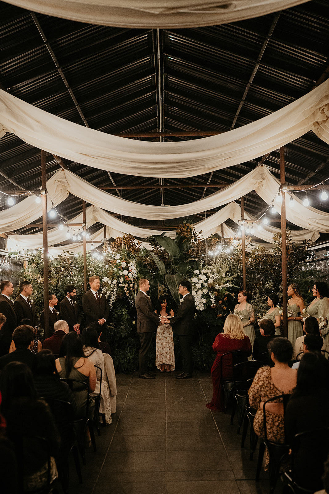 newlyweds holding ands during their ceremony in a greenhouse during their forest elopement in Oregon.