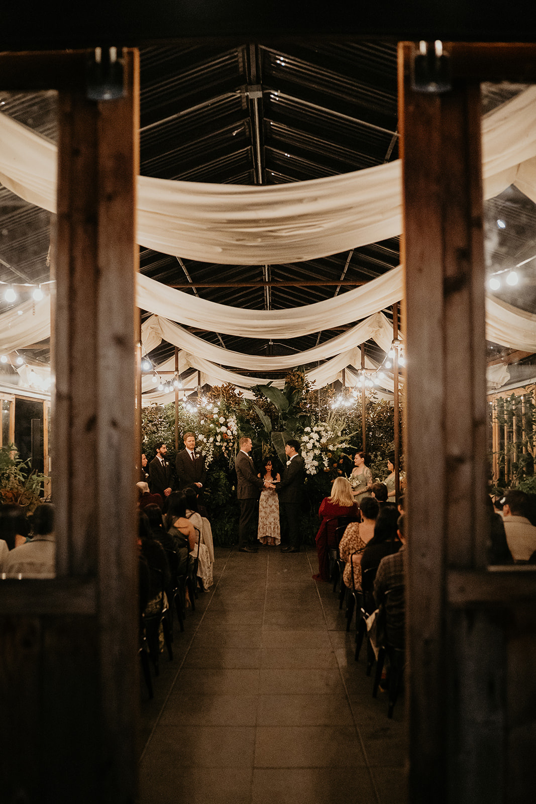 newlyweds holding hands during their wedding ceremony in a greenhouse during their forest elopement in Oregon.