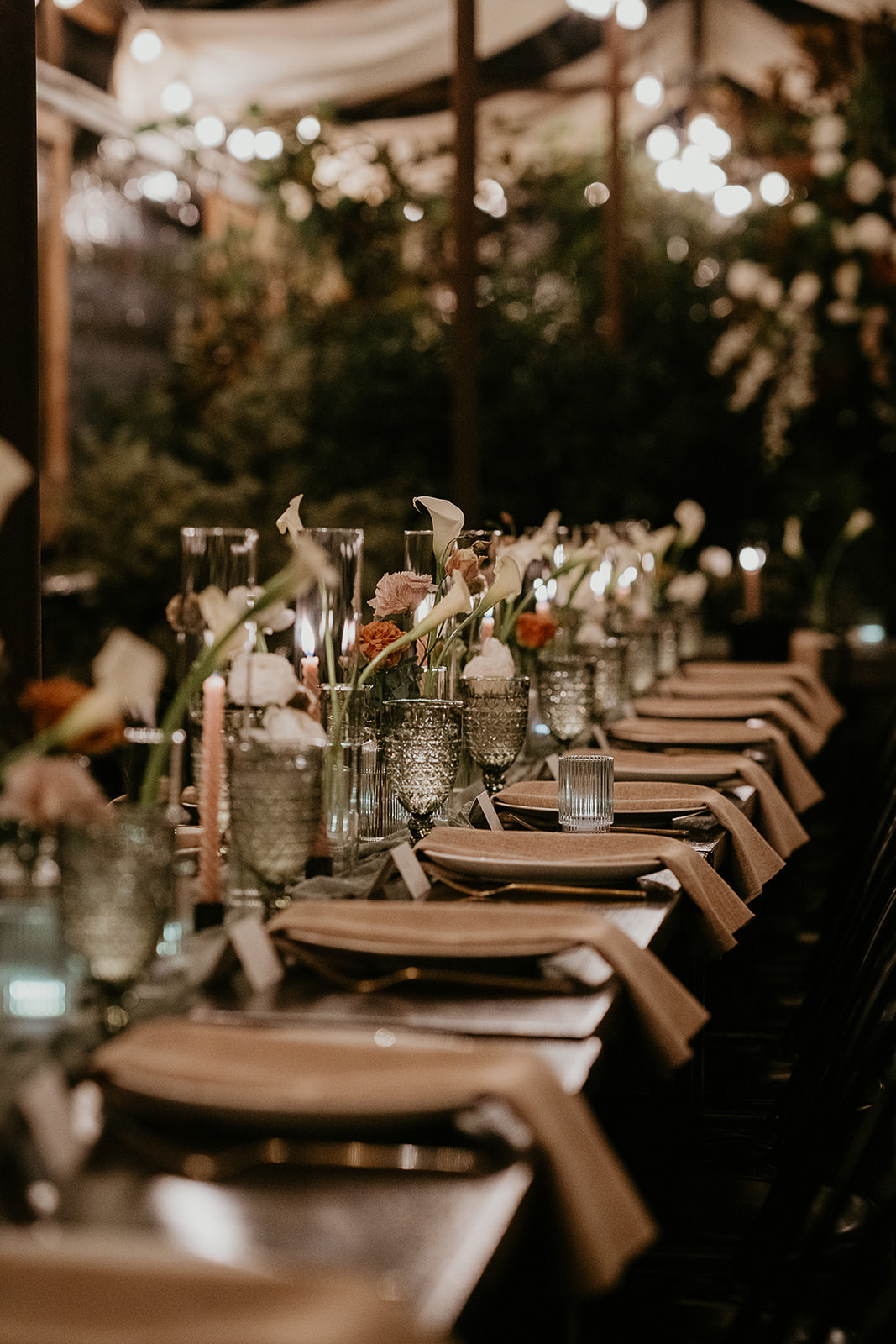 wedding dinner table with candles, flowers, and table settings.