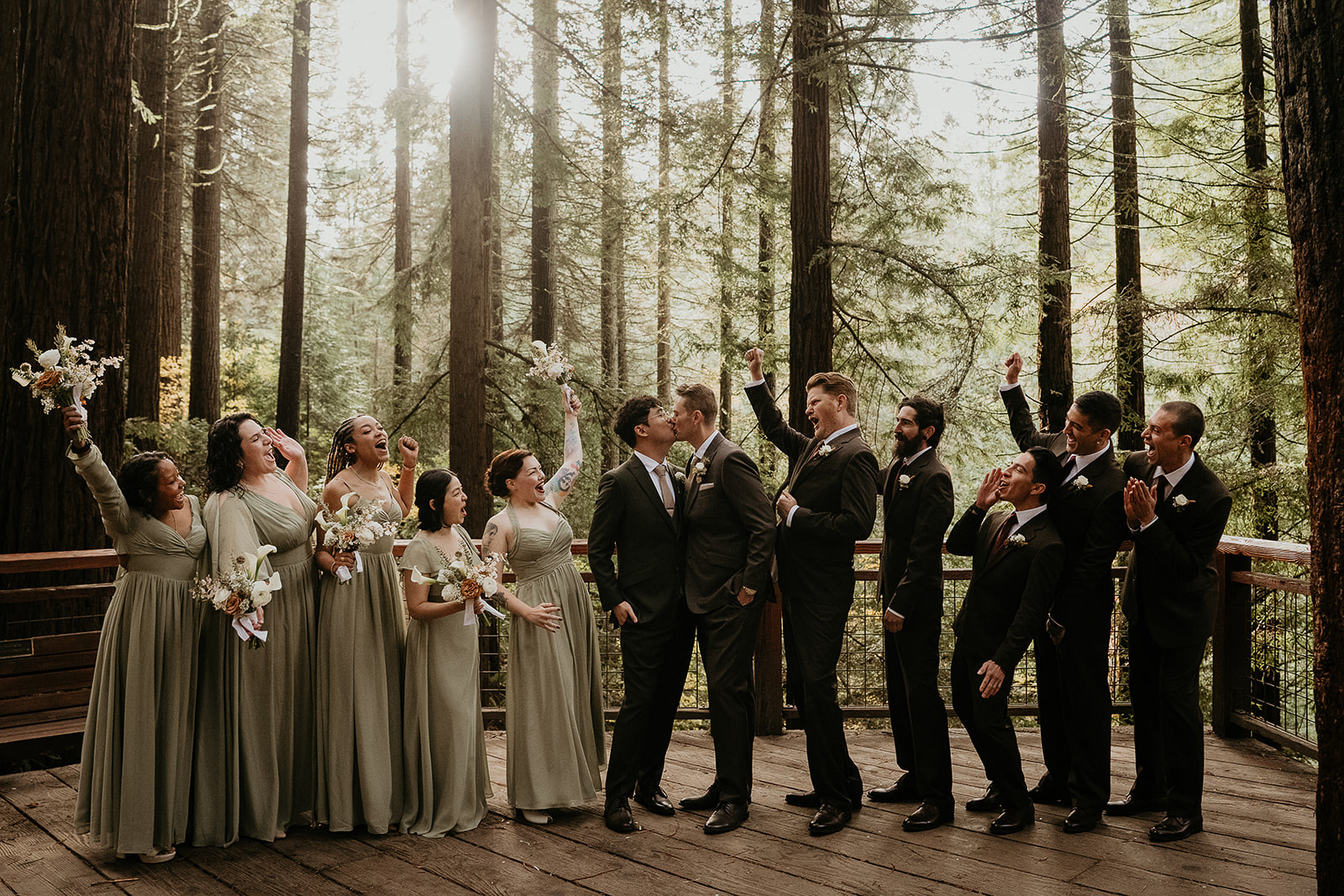 newlyweds kissing with their wedding party cheering them on during their forest elopement in Oregon.