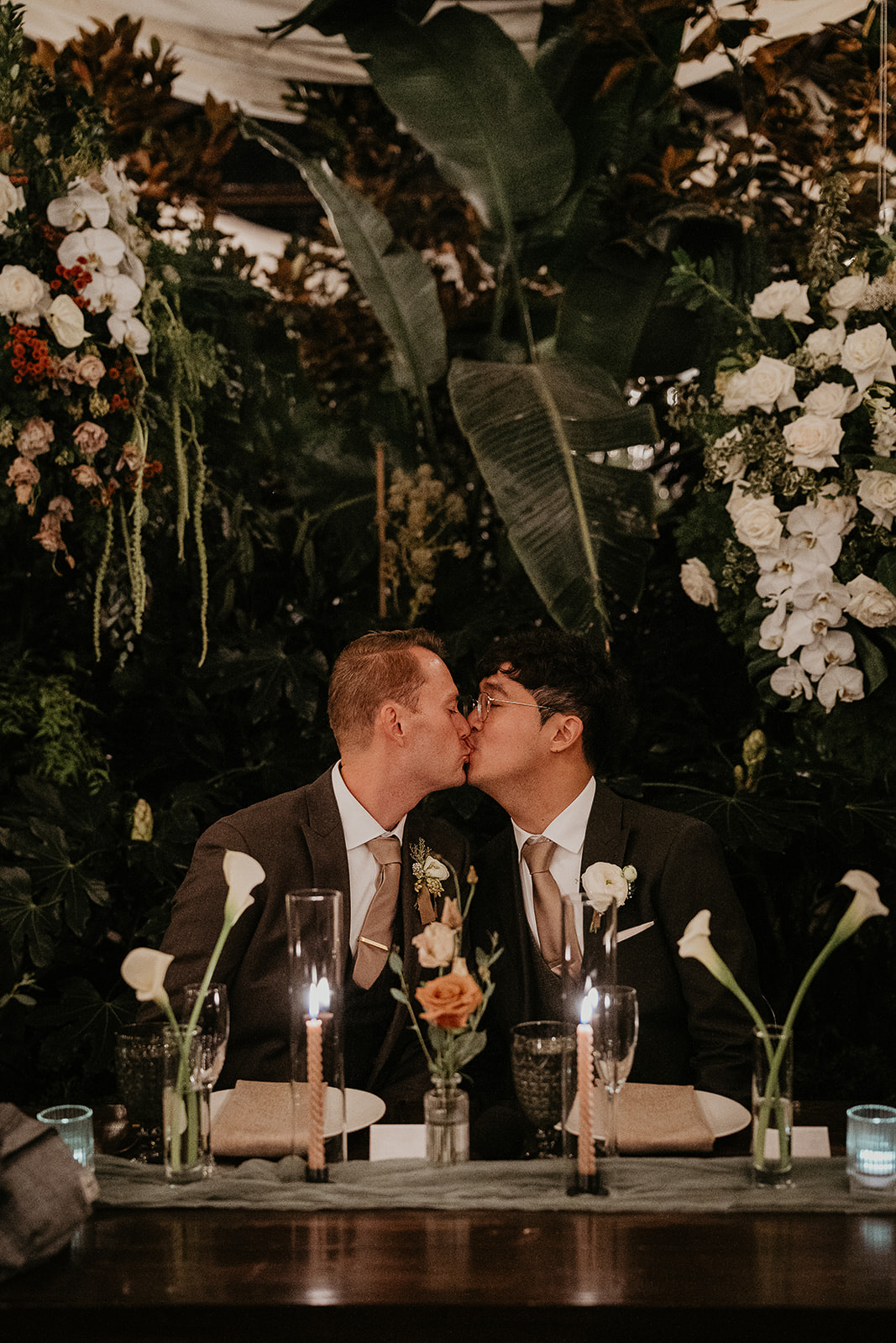 newlyweds kissing sitting at their reception table during their forest elopement in Oregon.