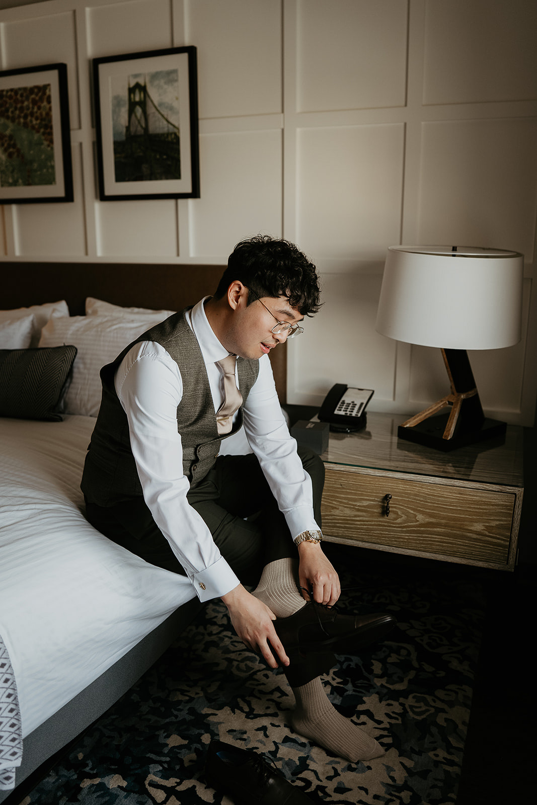 groom putting on his shoes in a hotel room during his forest elopement in Oregon.