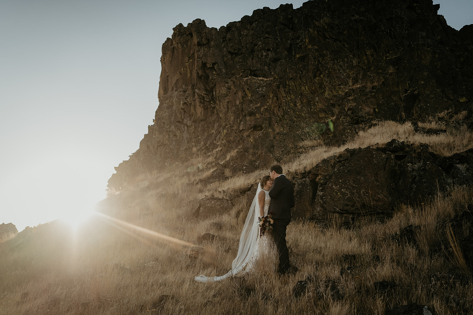 newlyweds kissing while standing in a field of golden grass during their Columbia River Gorge elopement.