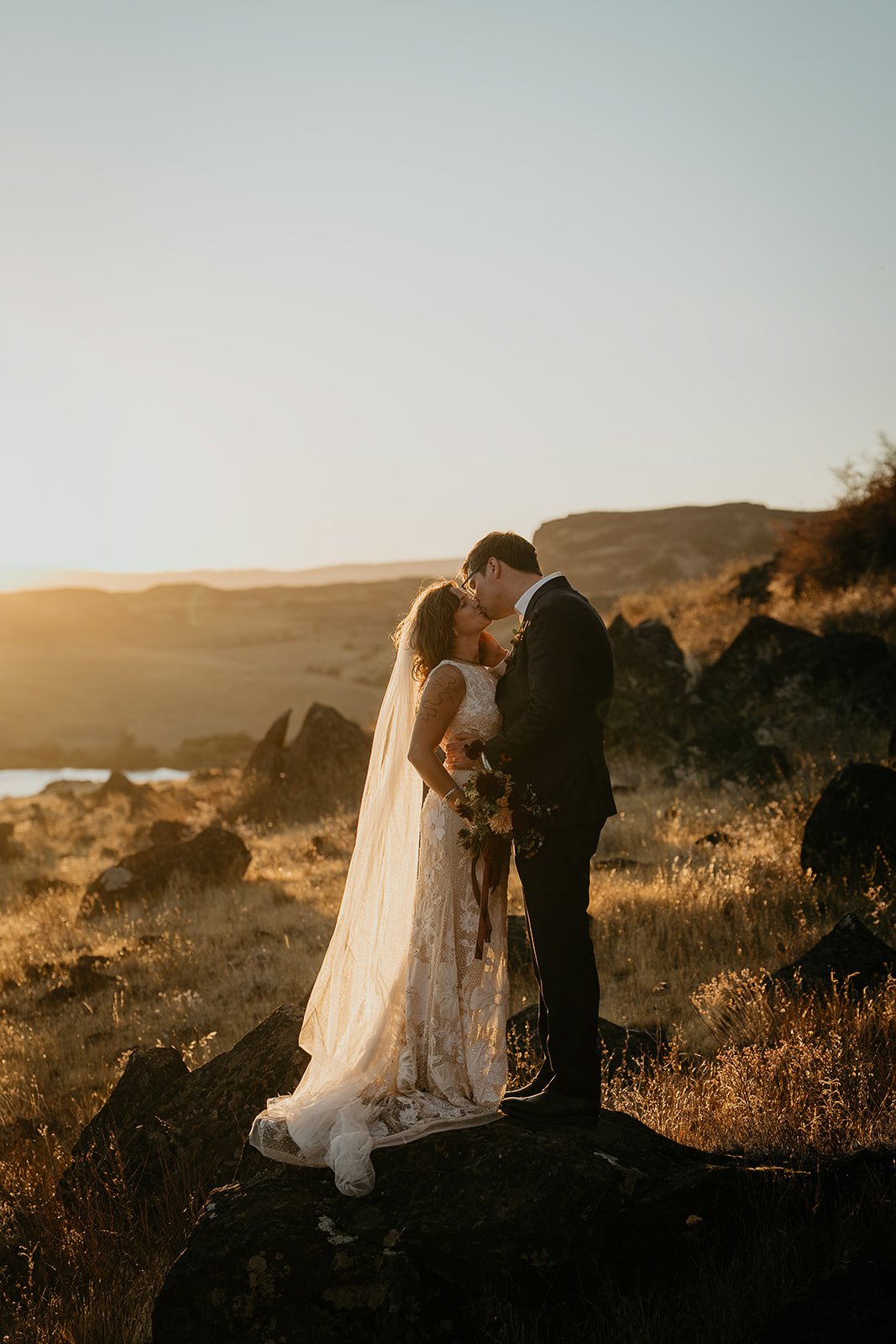 newlyweds kissing in a meadow at sunset during their columbia river gorge elopement.