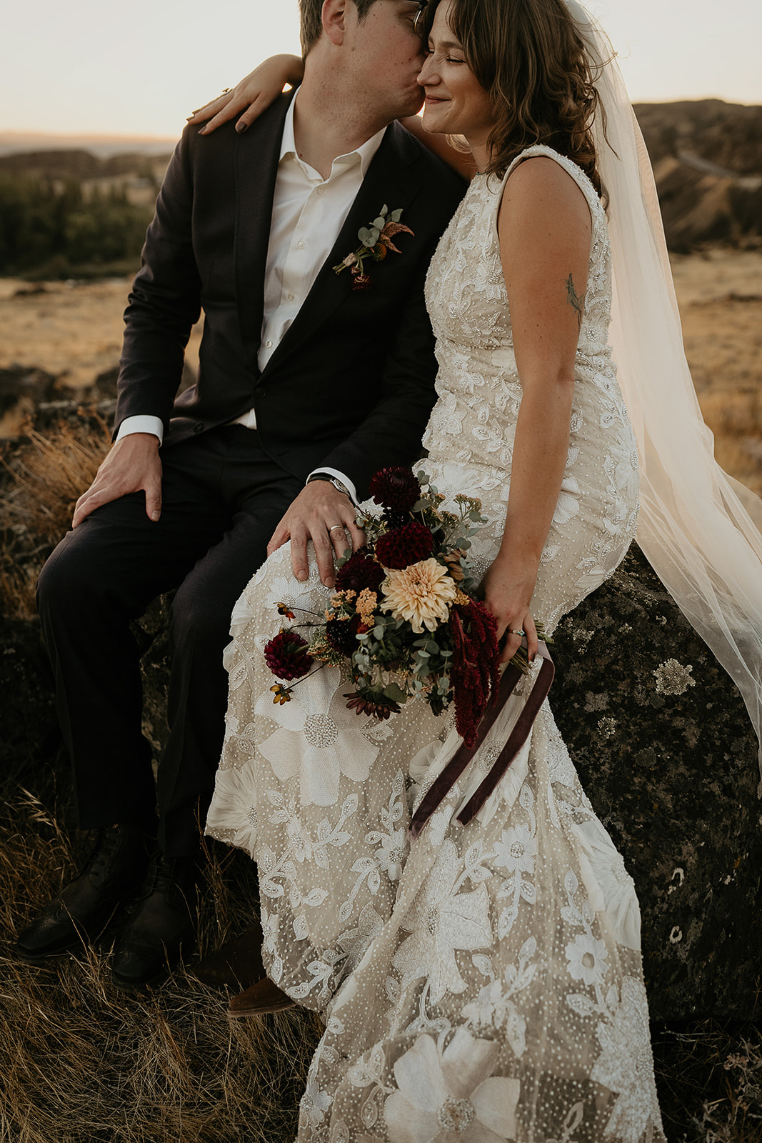 newlyweds kissing at sunset in a meadow.