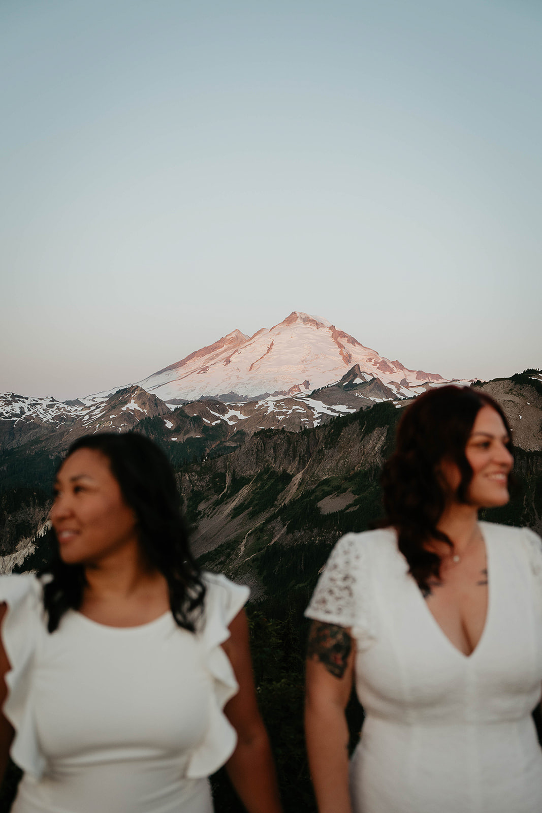 newlyweds looking in opposite directions as the alpenglow illuminates the mountain behind them.