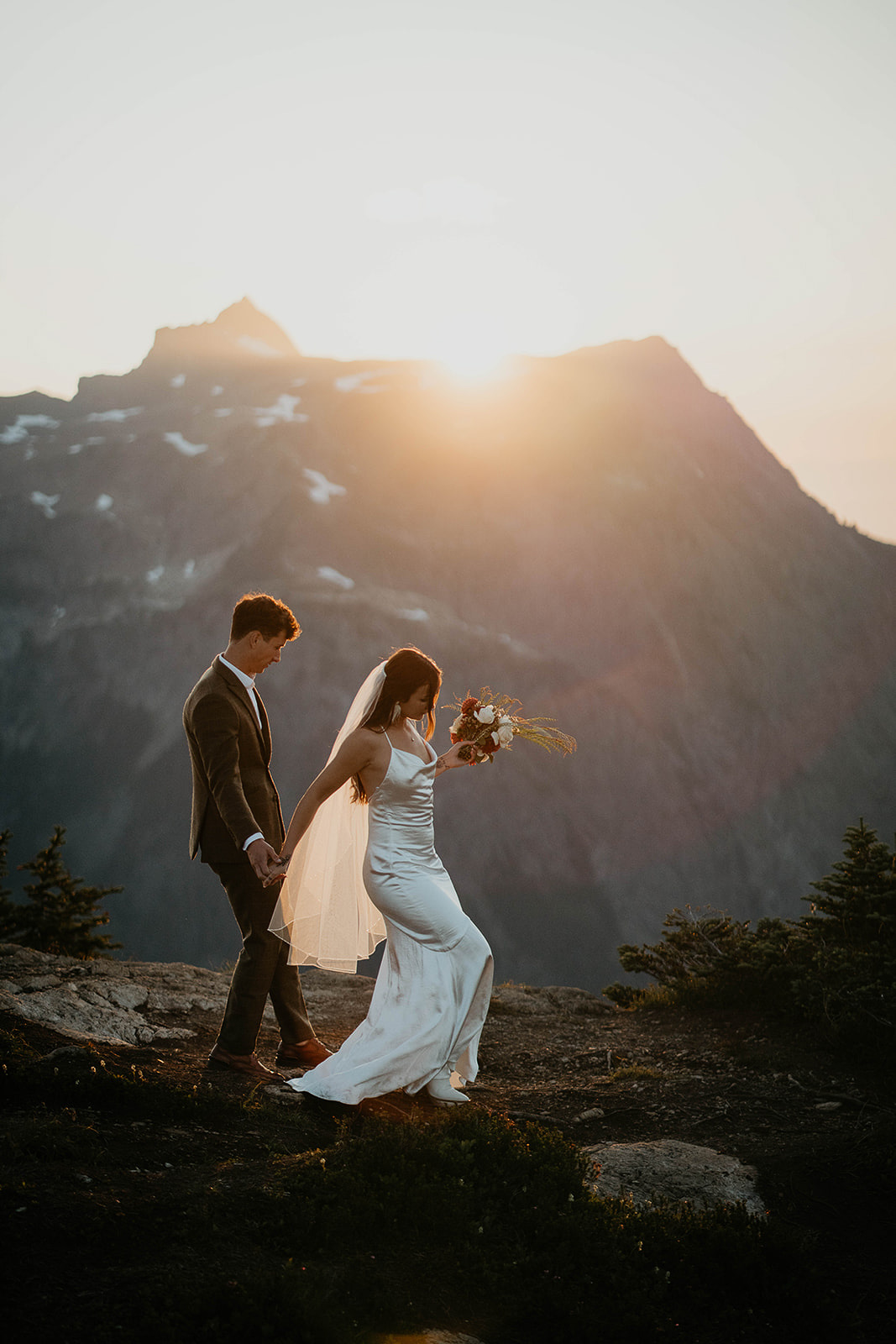 newlyweds hiking in the mountains as they elope at sunset.