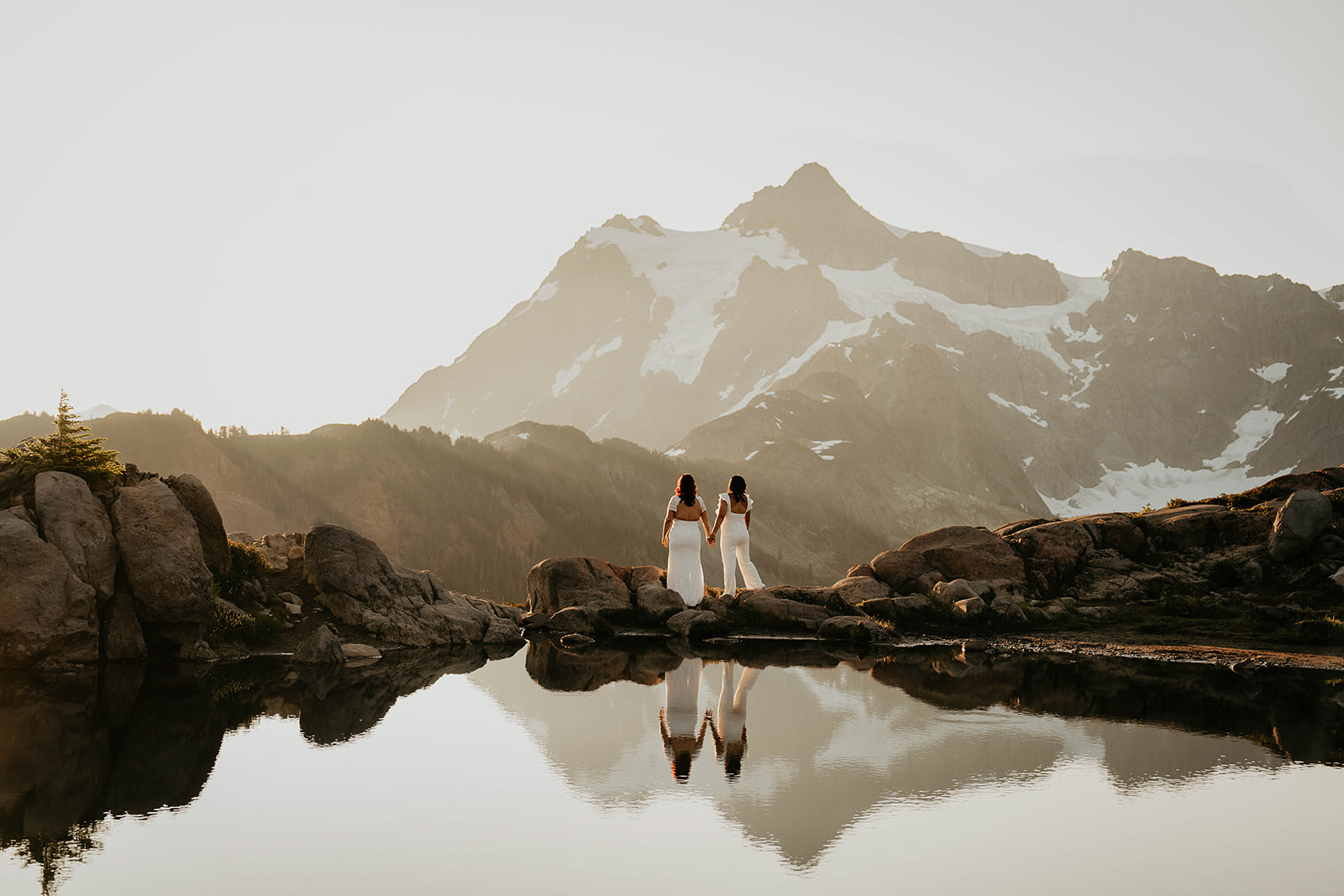 newlyweds holding hands as they enjoy a mountain sunrise.
