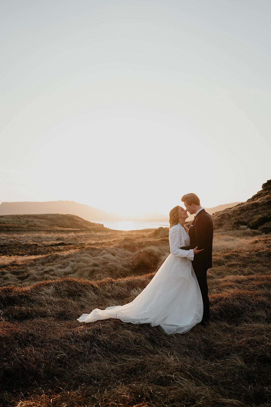 newlyweds hugging each other in a meadow as they elope at sunrise.