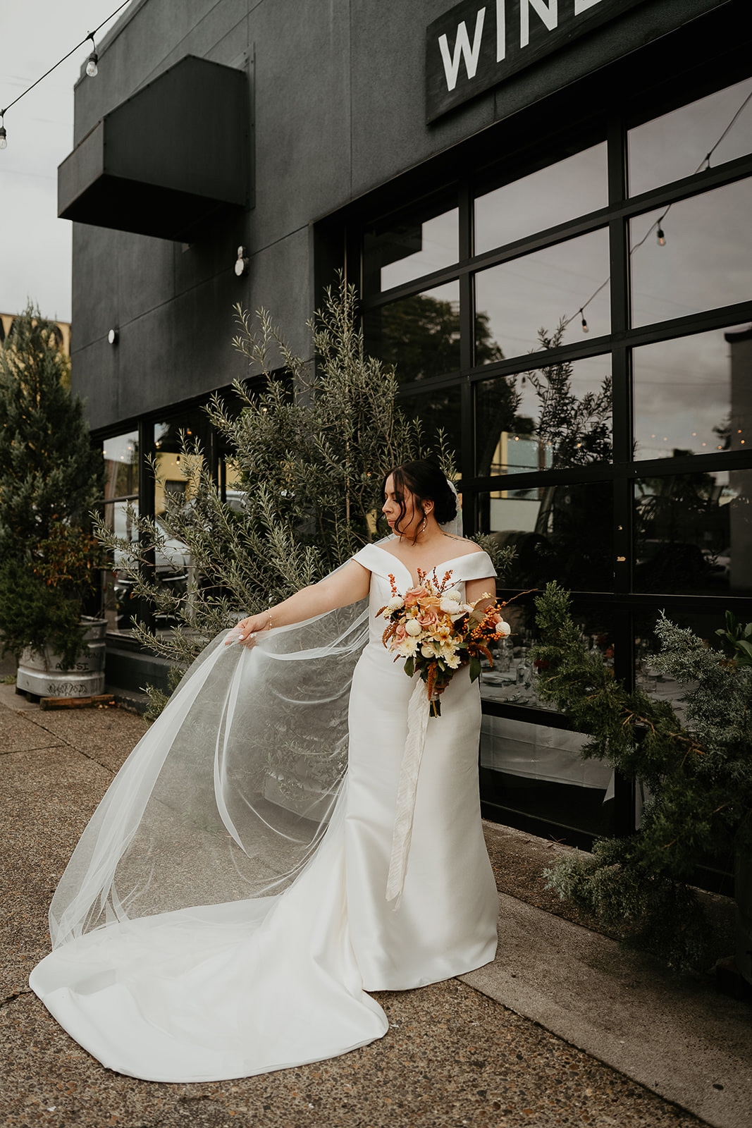 bride holding out her veil in front of Coopers Hall winery.