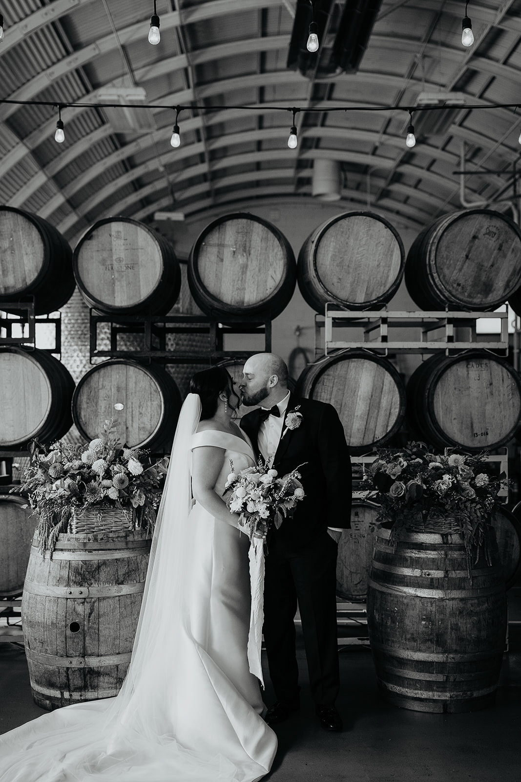 newlyweds kissing in front of wine barrels during their Coopers Hall wedding.