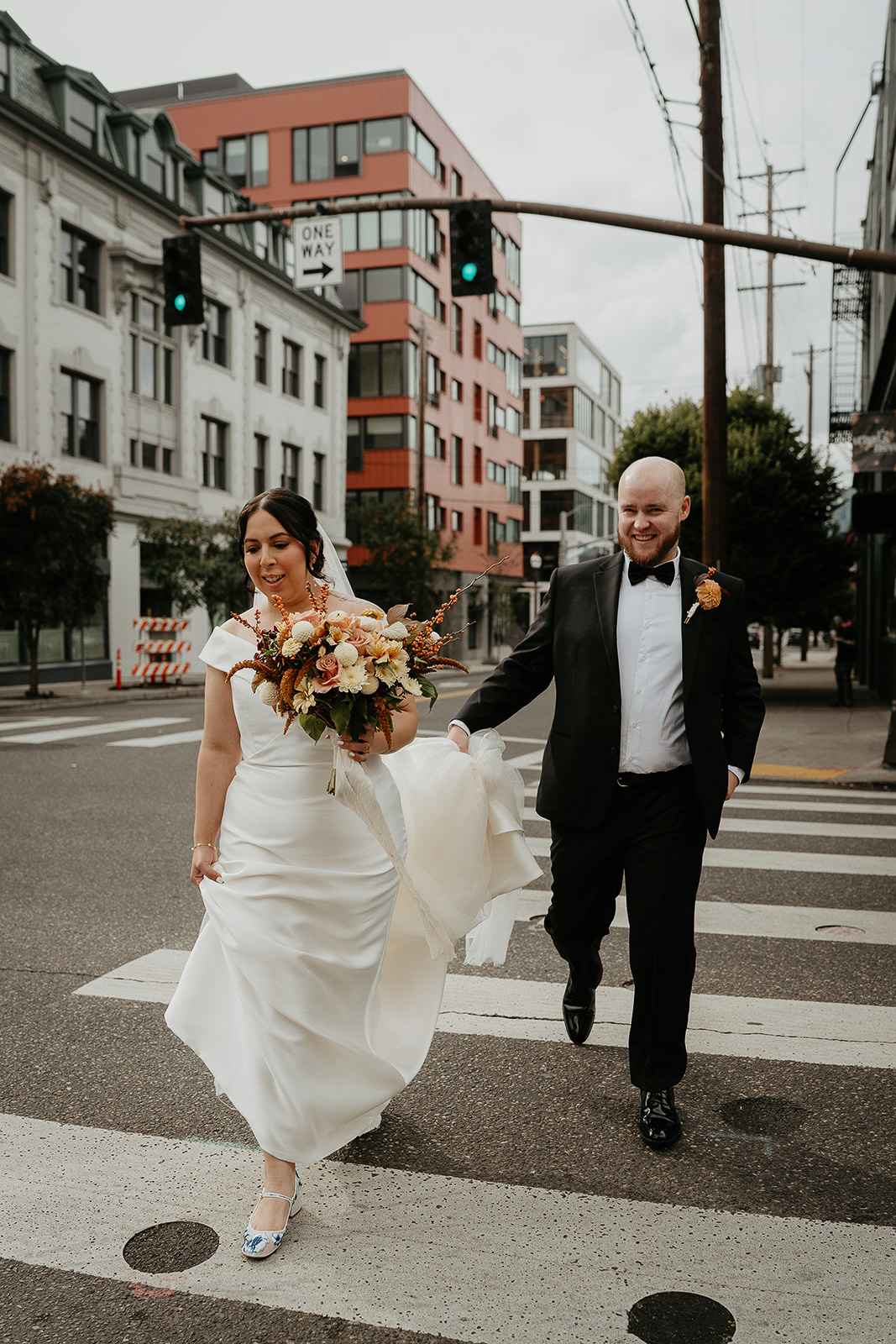 newlyweds walking across a portland crosswalk during their Coopers Hall wedding.