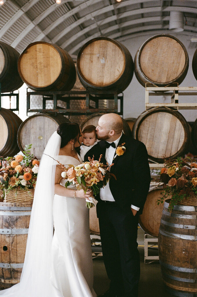 newlyweds kissing the cheeks of their son.