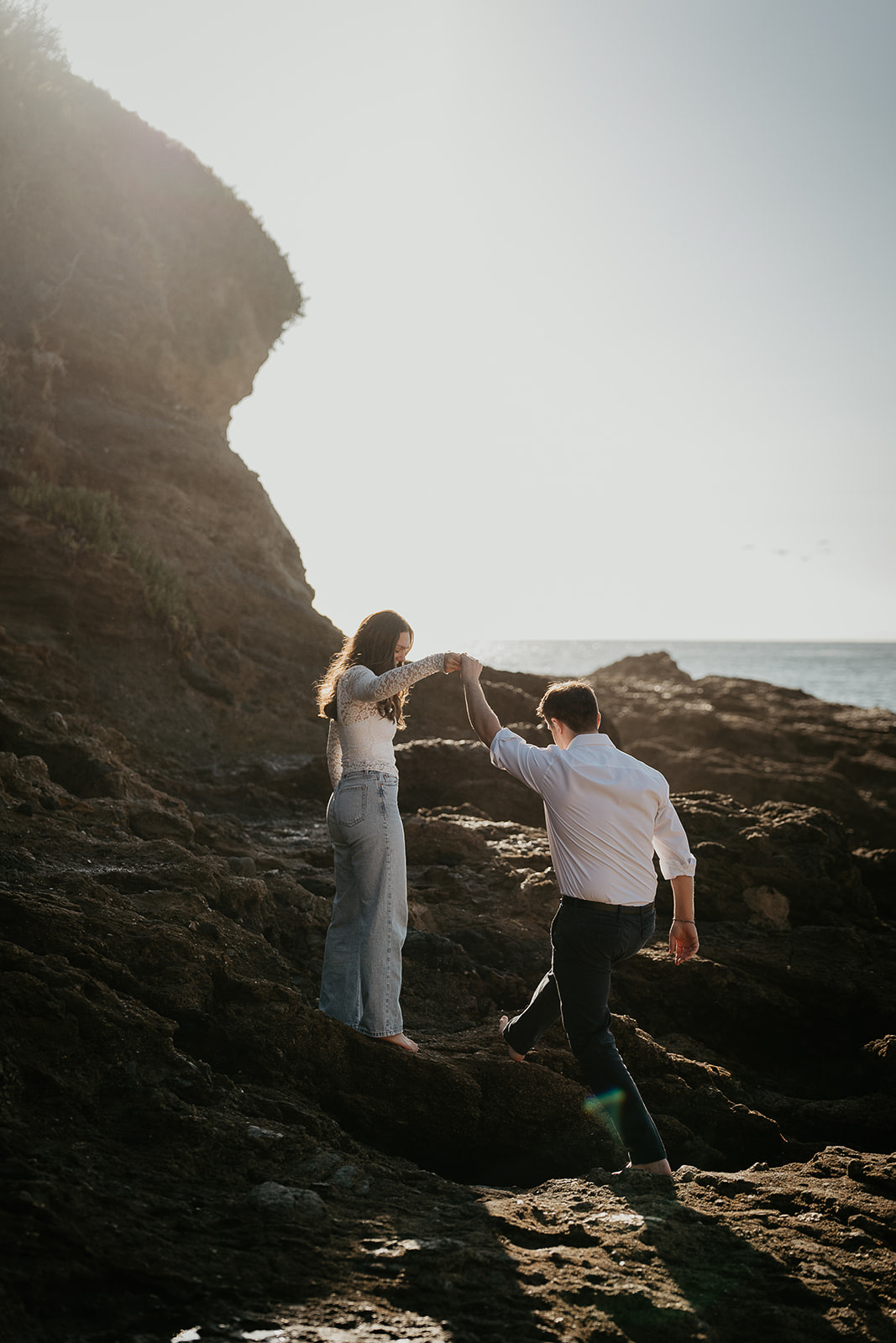 couple walking along the rocky shoreline during their Laguna Beach engagement.