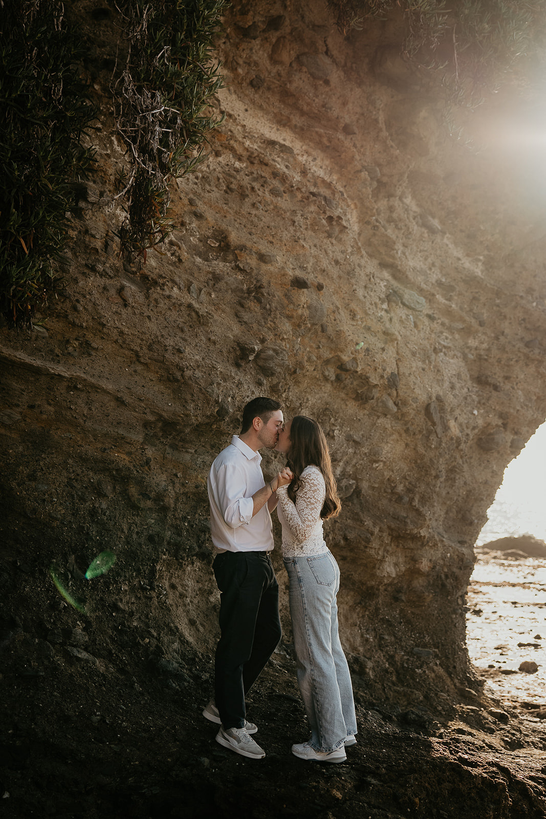 couple kissing next to a cliff by the ocean during their Laguna Beach engagement.