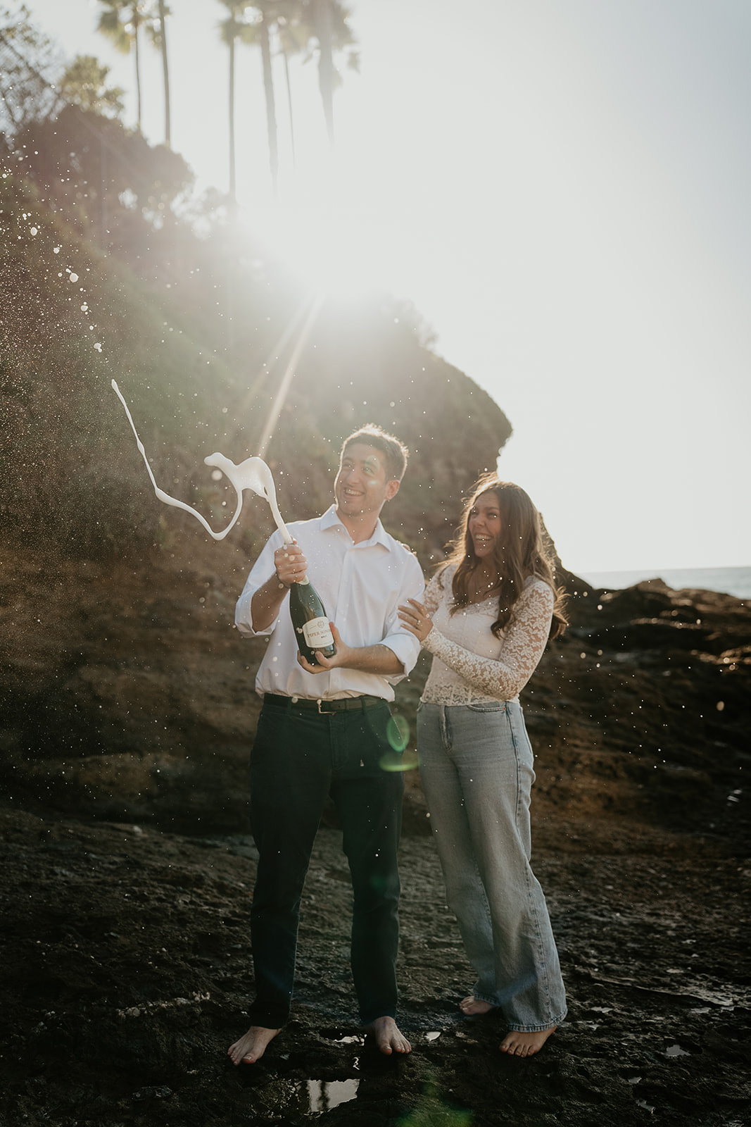 couple spraying champagne at the beach.
