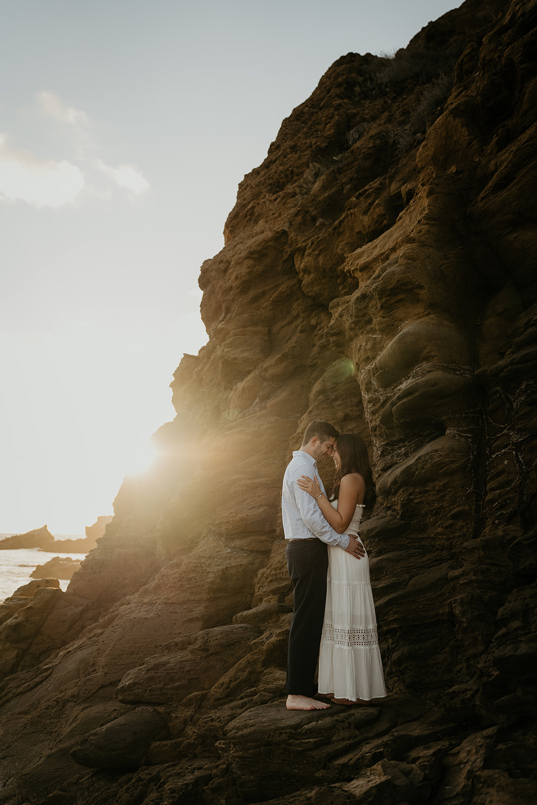 couple hugging on a rocky shoreline during their Laguna Beach engagement.