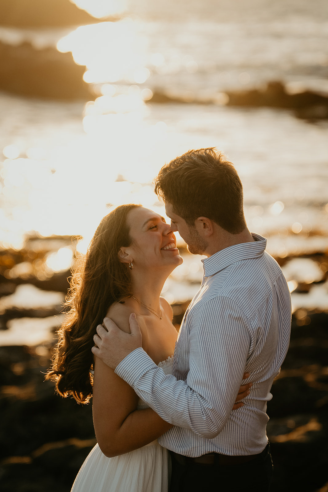 couple hugging about to kiss with the ocean behind them