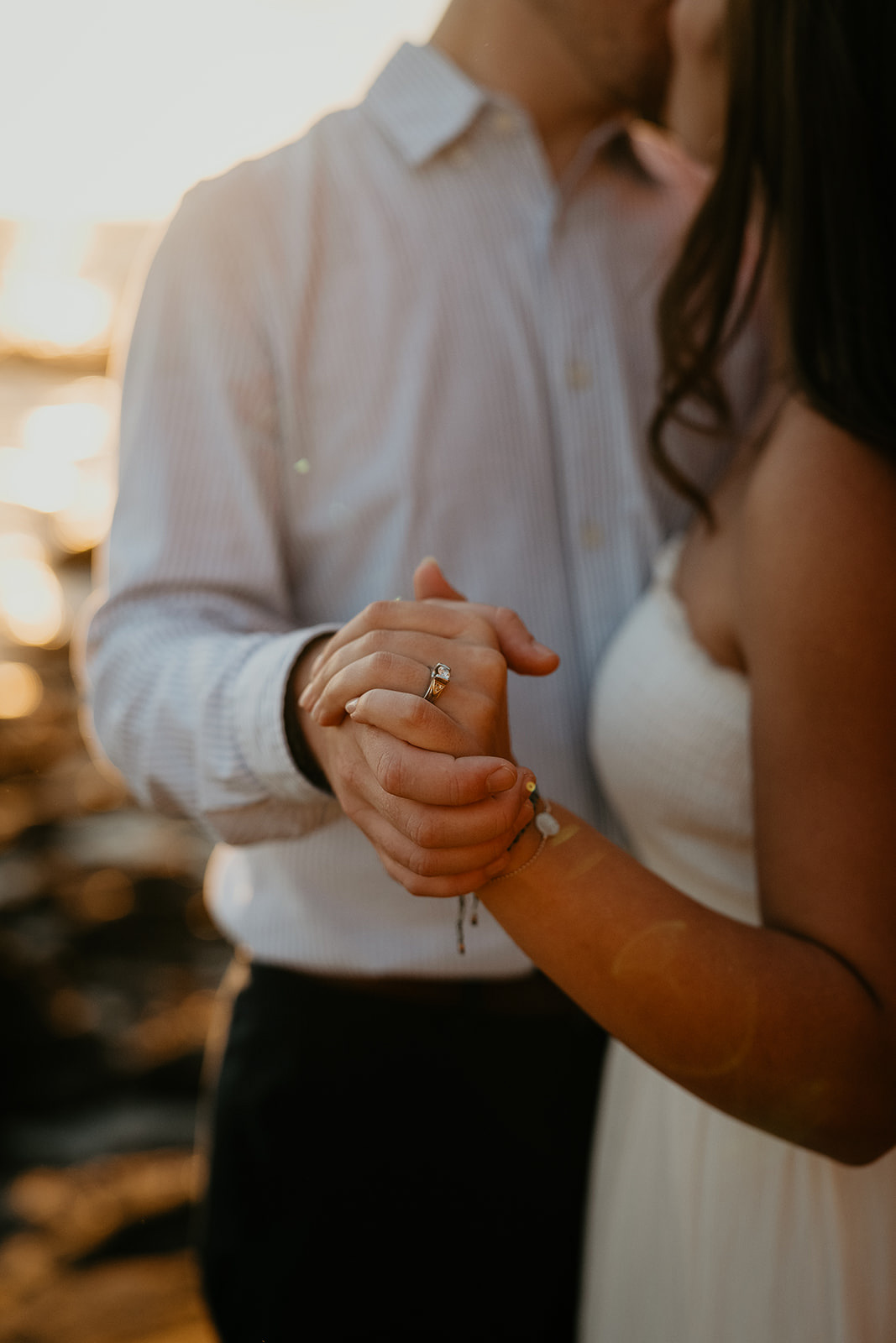 couple holding hands, the girlfriend showing off her engagement ring.
