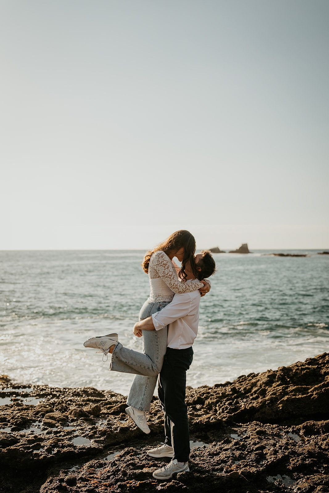 couple kissing on the rocky shoreline.