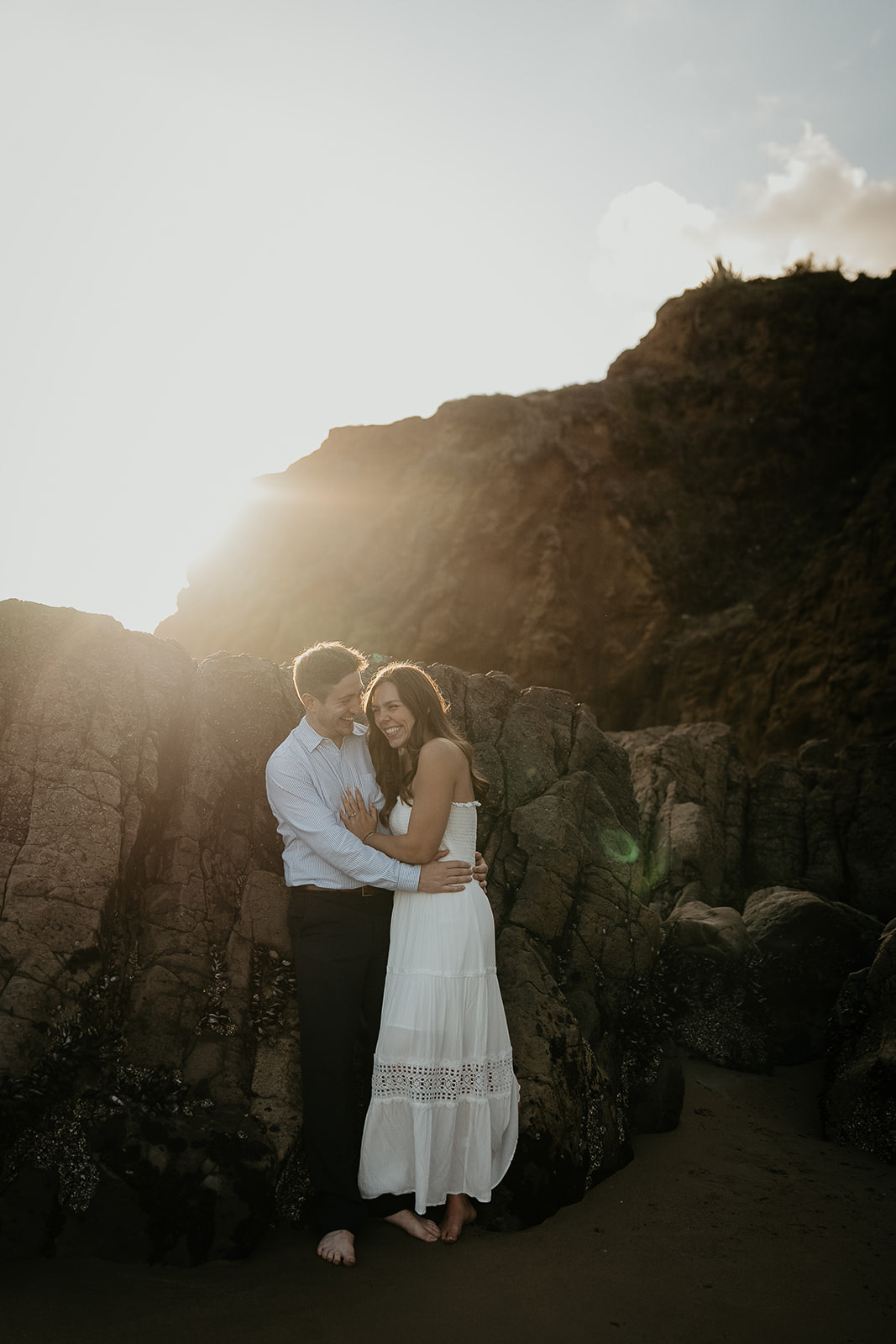 couple hugging next to some ocean rocks during their Laguna Beach engagement.