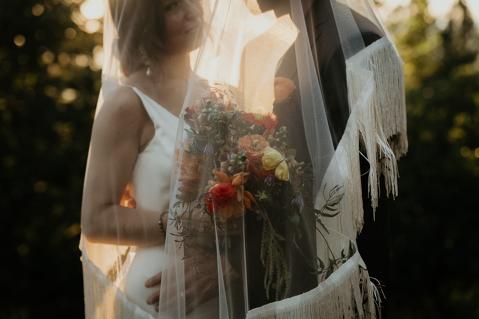 newlyweds under the bride's veil at sunset during their vintage inspired wedding.
