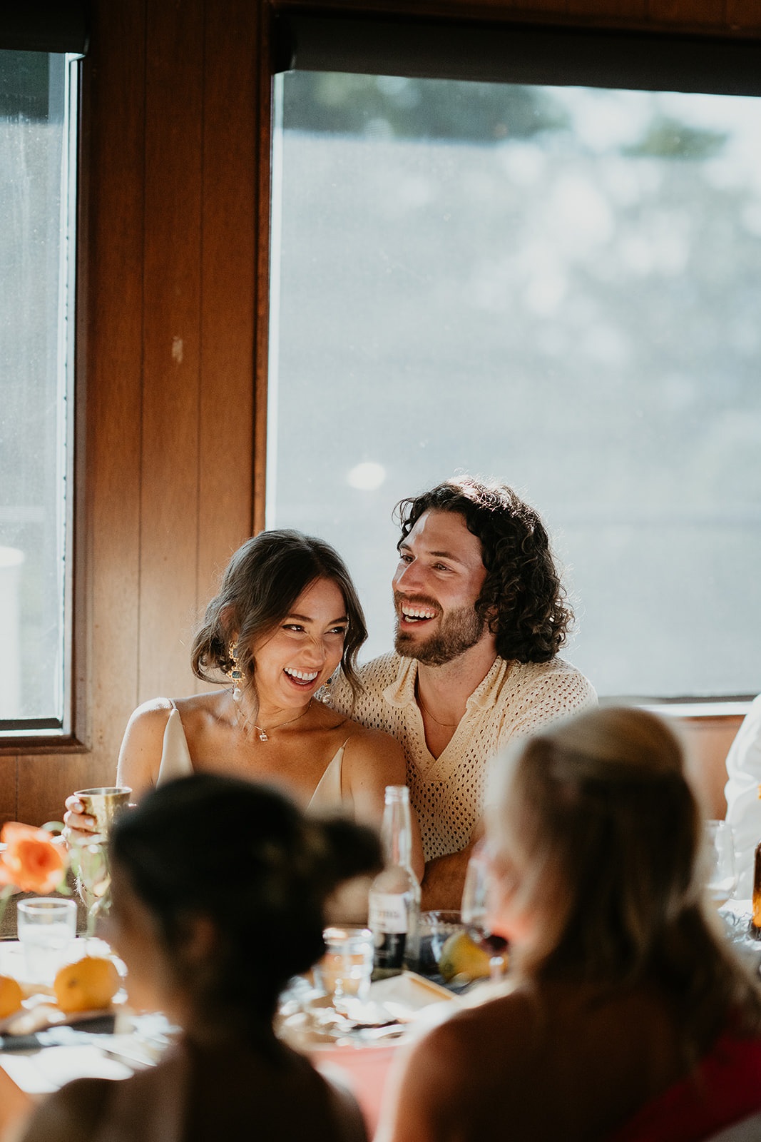 the newlyweds hugging and smiling at the dinner table during their vintage inspired wedding.