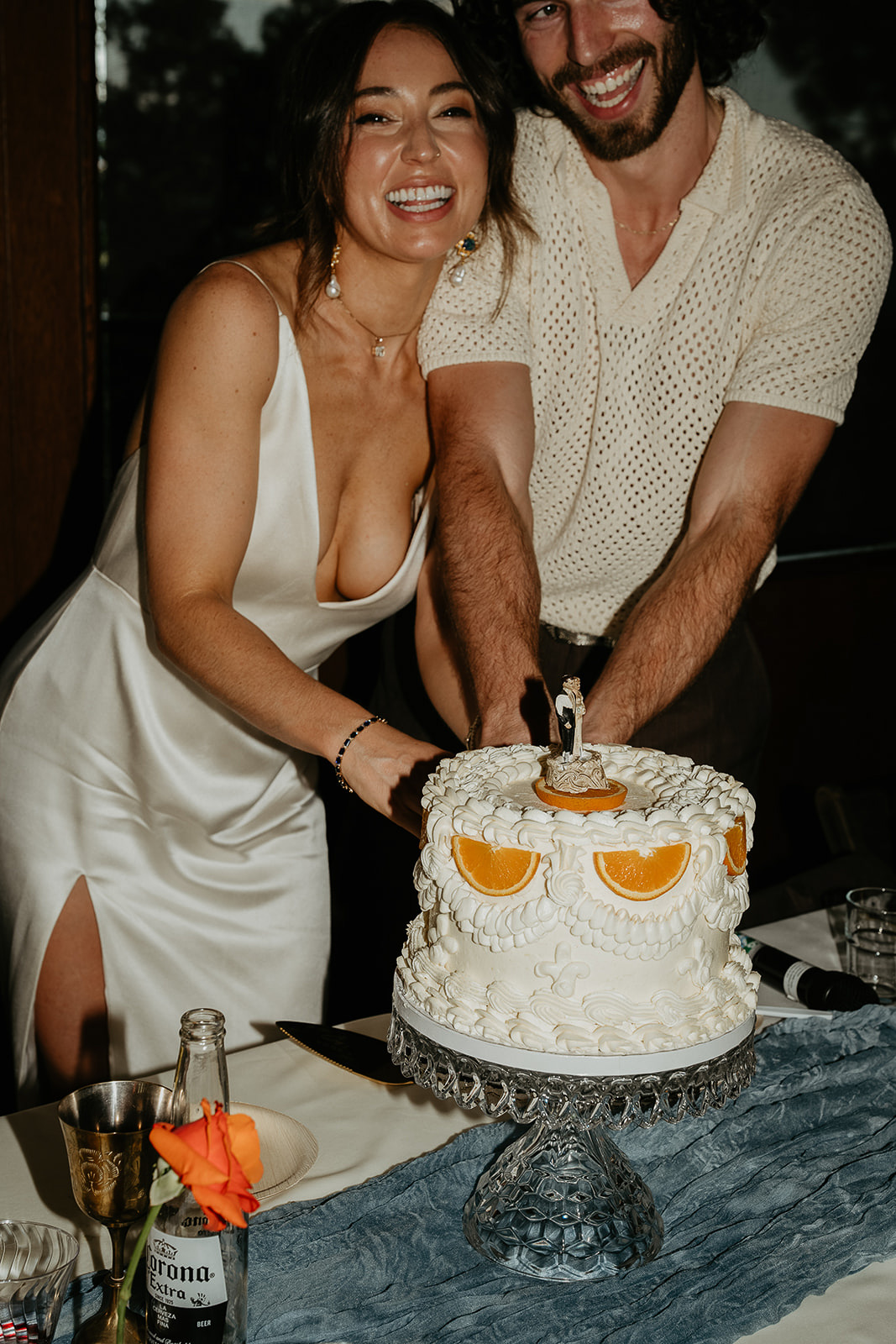 the newlyweds cutting their wedding cake and smiling.