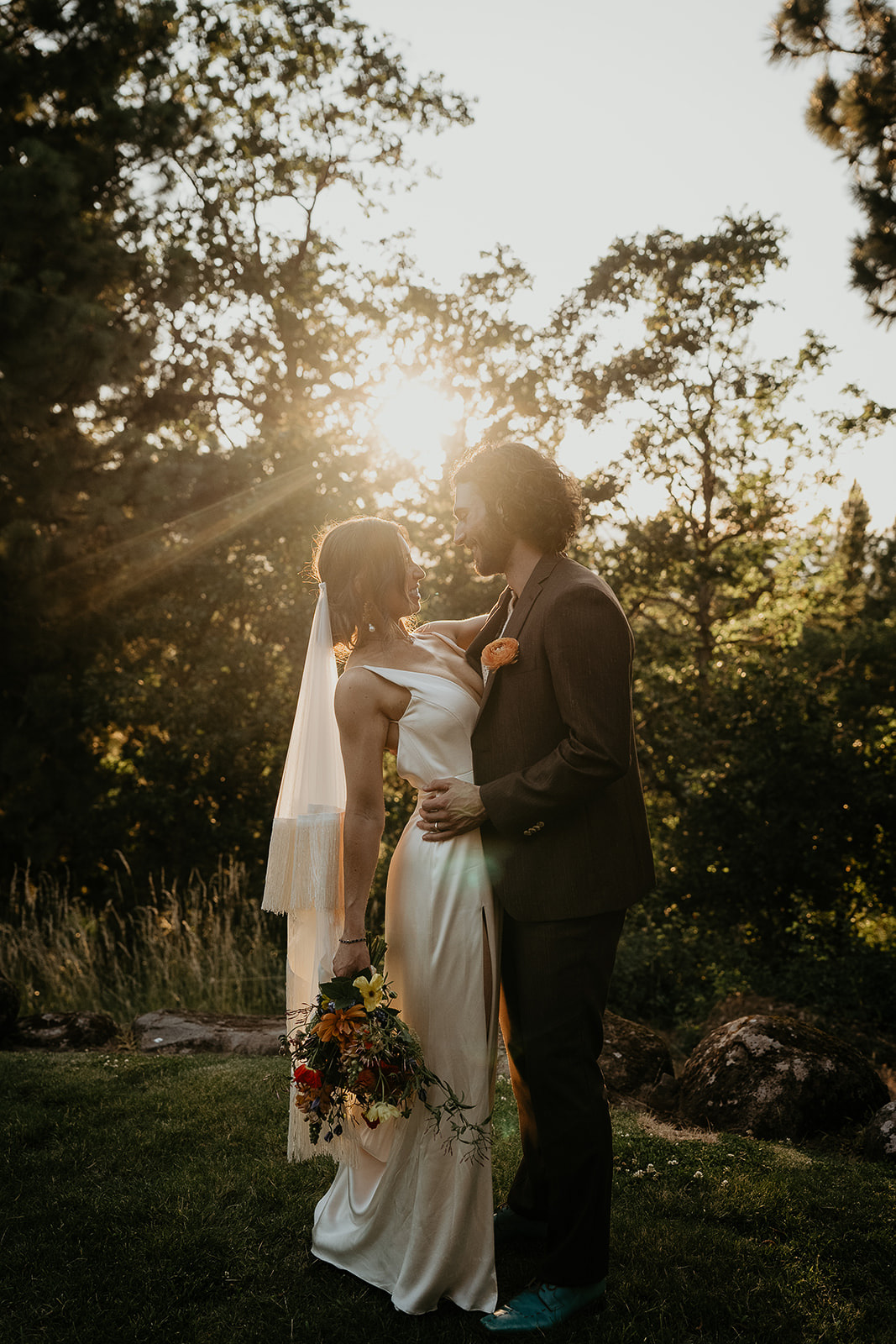 newlyweds hugging and smiling at sunset during their vintage inspired wedding.